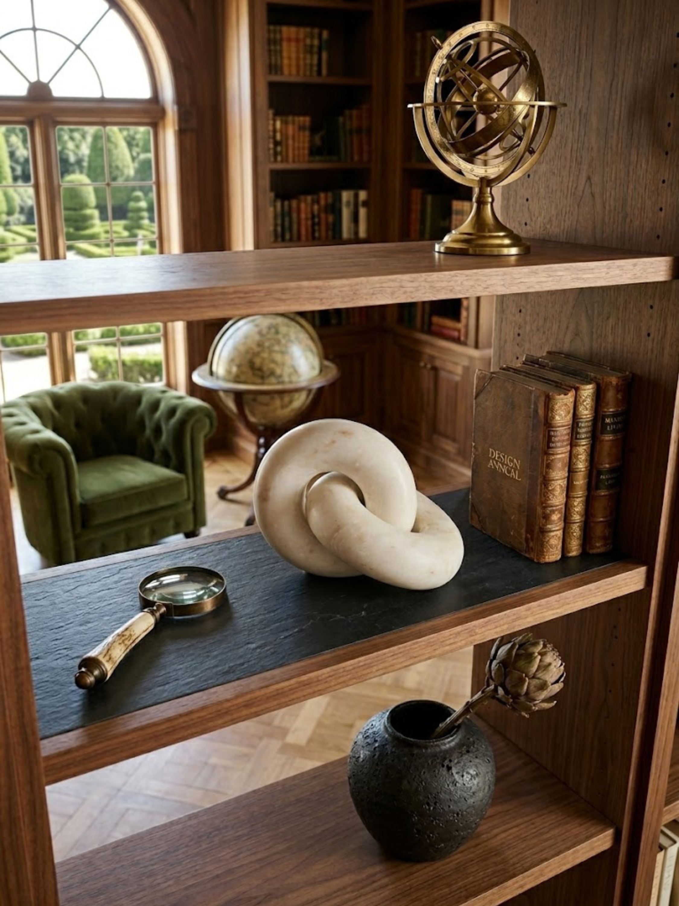 Munich white marble decorative knot resting on a bookshelf, showcasing fluid sculptural form among collected books and curated study objects.