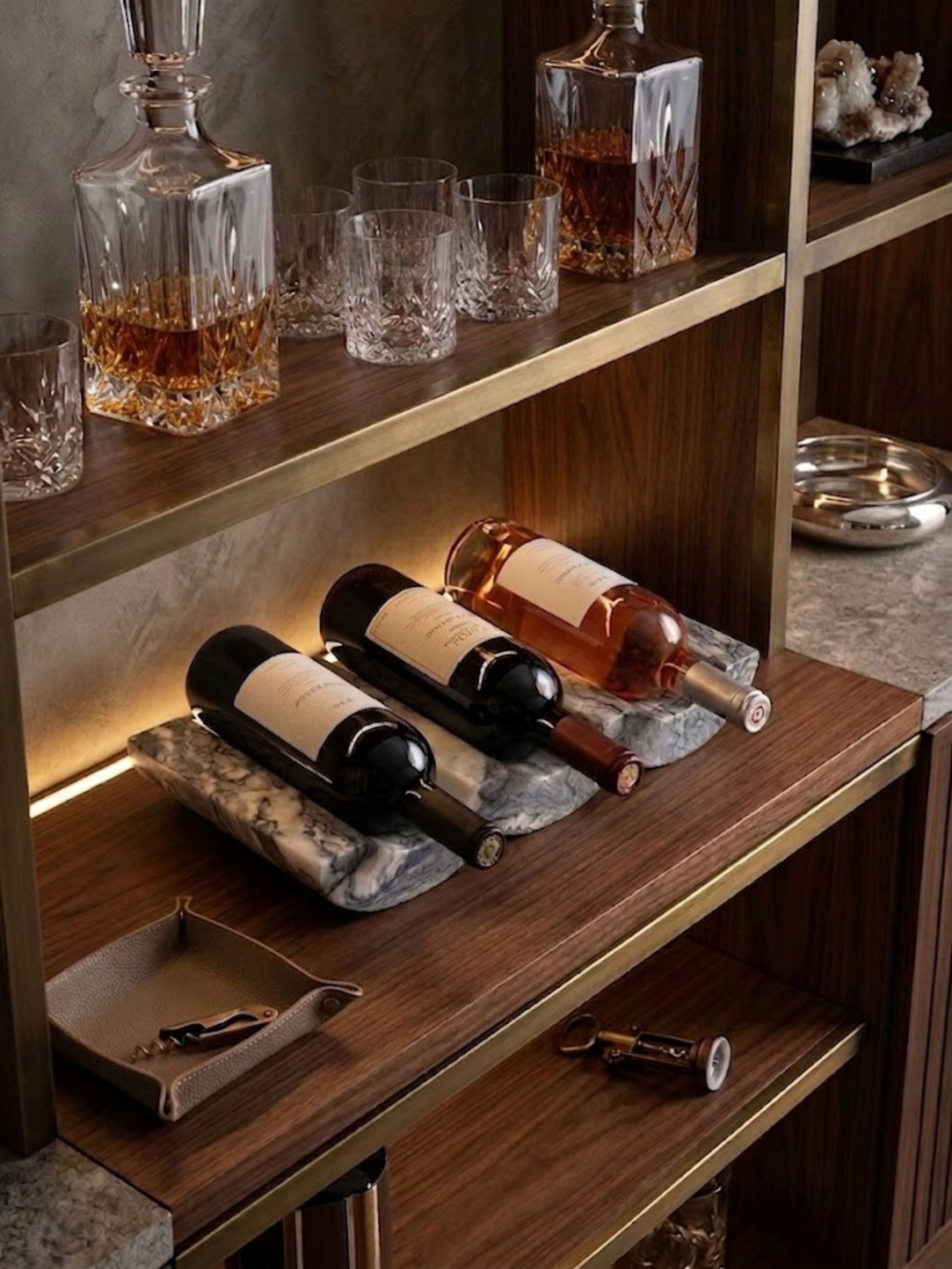 Georgia brown onyx wine bottle holder displayed on a walnut bar shelf, showcasing three bottles and the stone’s rich caramel, cream, and espresso-toned veining.