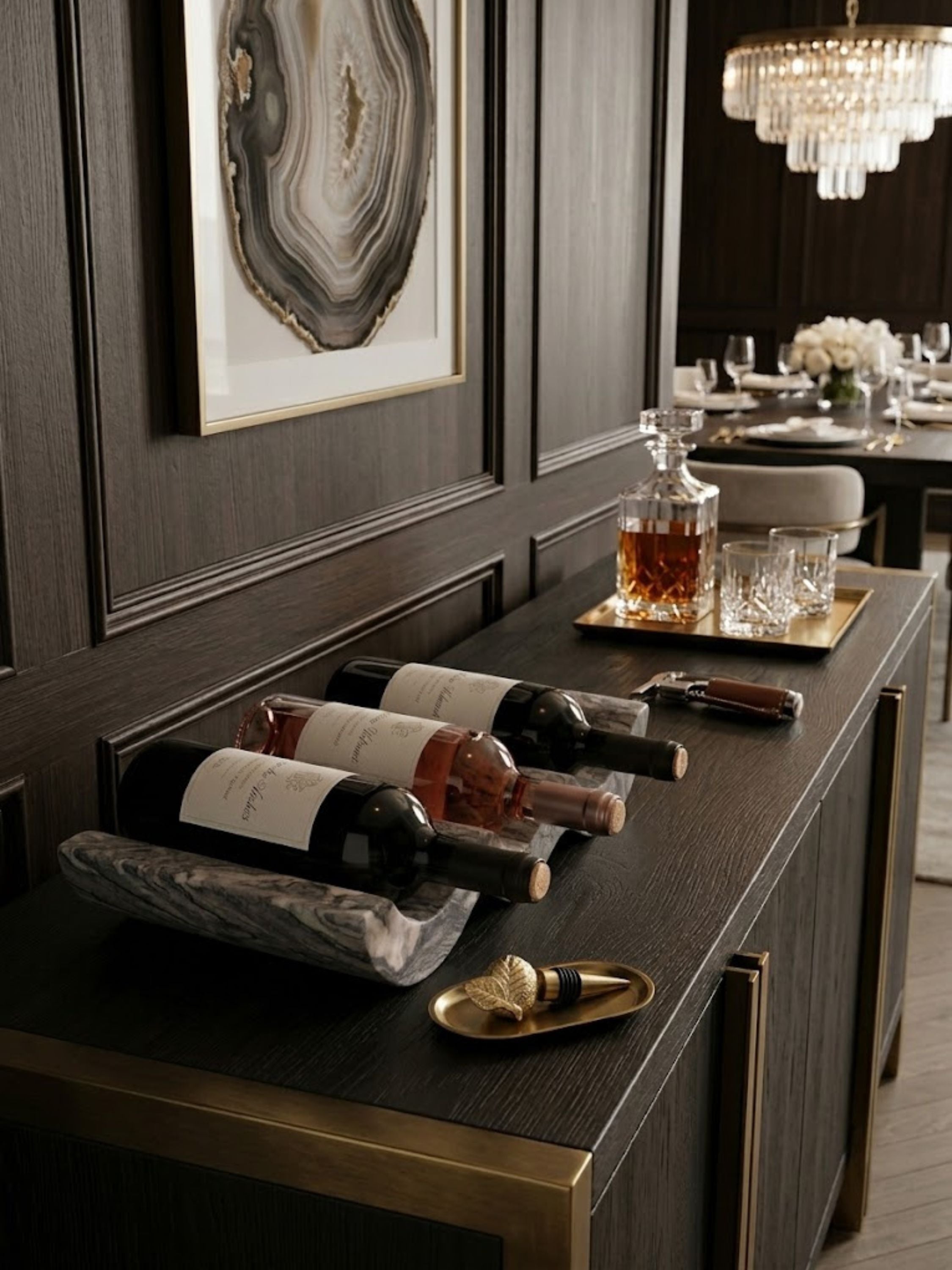 Brown onyx wine bottle holder styled on a dining console with wine service accessories, highlighting sculptural form and layered natural stone movement.
