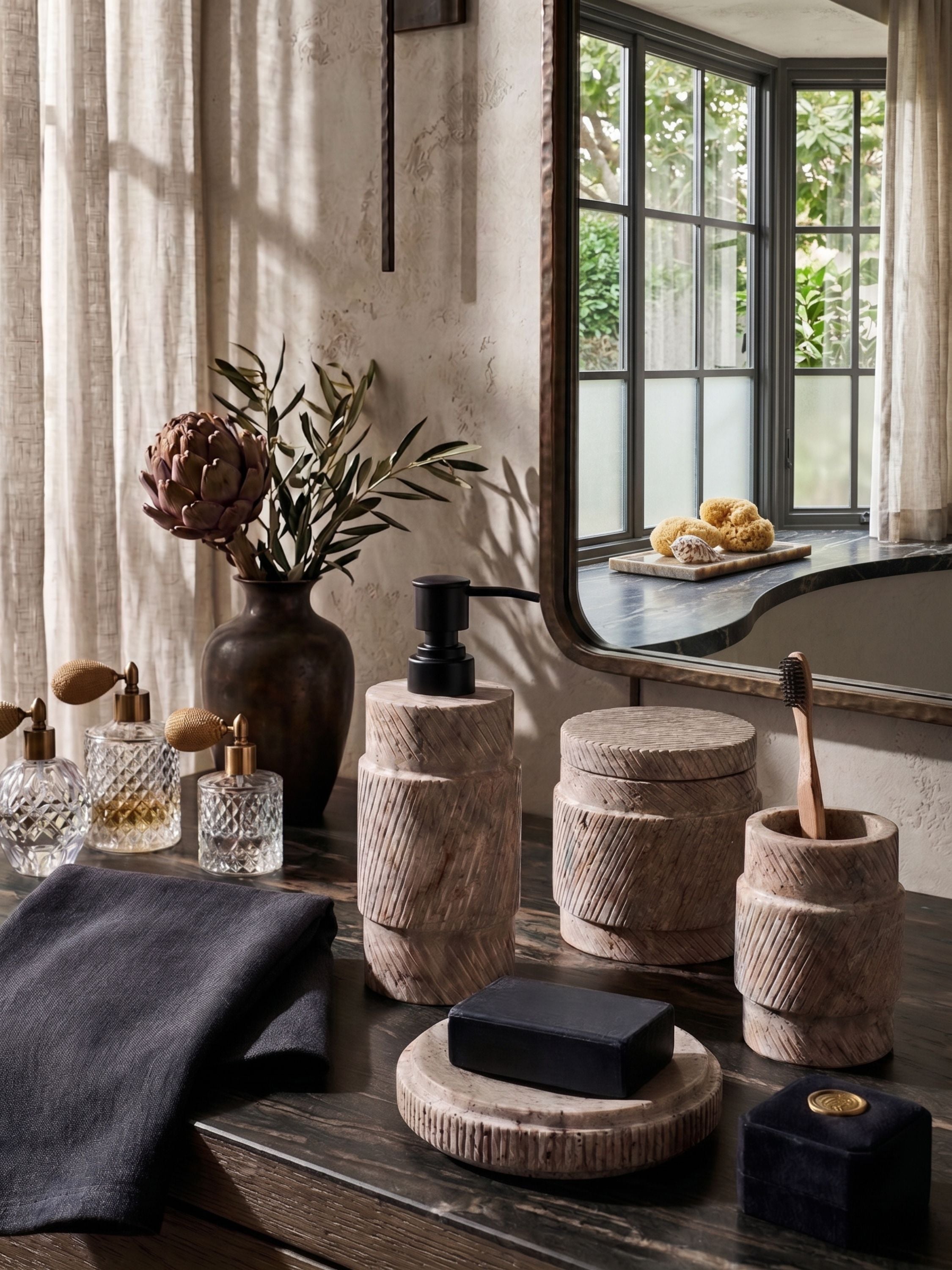 Hand-carved marble bath accessories styled on a vanity with mirror, towels, and decor accents