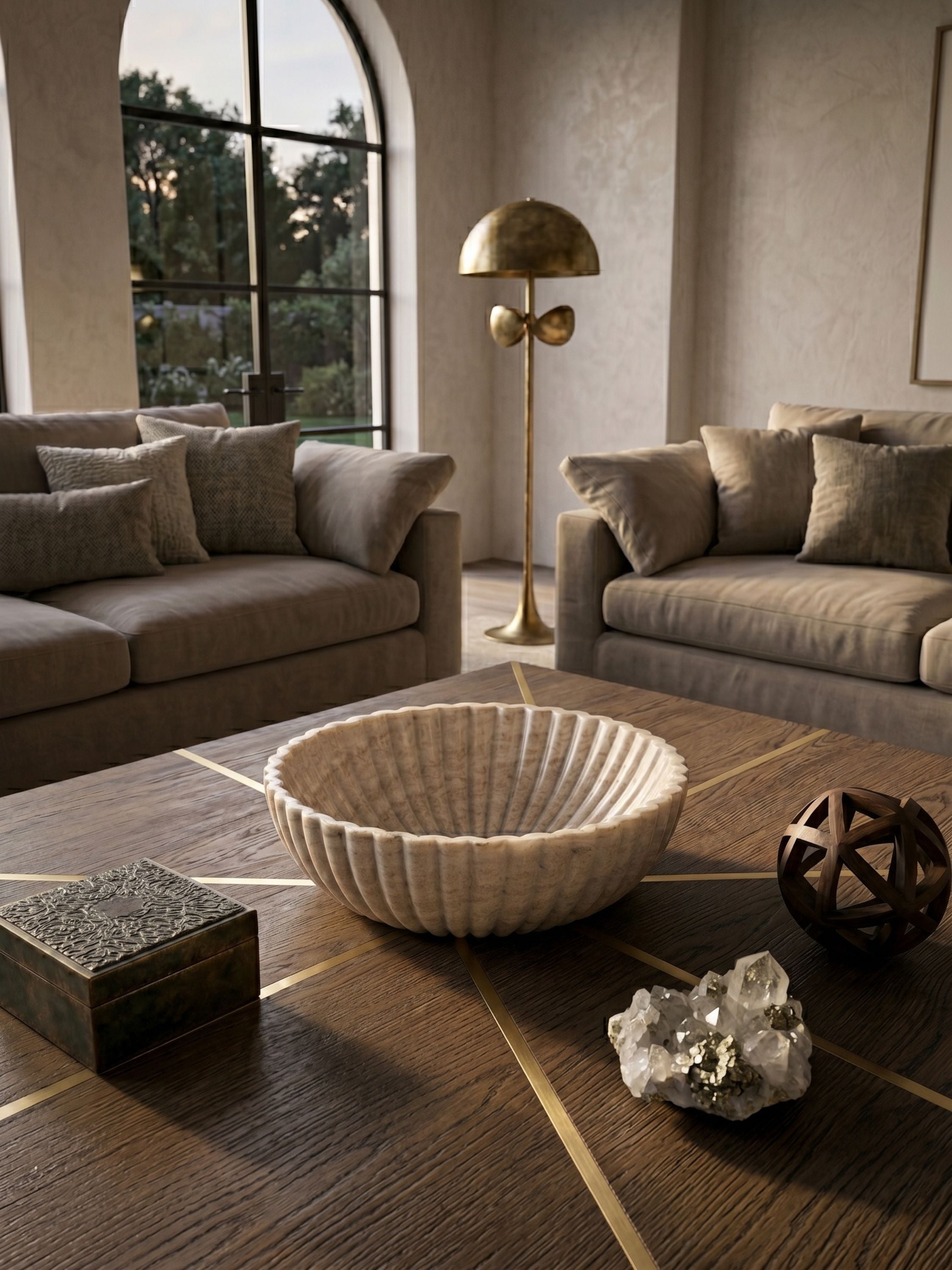 Fluted beige onyx centerpiece bowl displayed on a coffee table, showcasing carved detailing, tonal stone movement, and a calm architectural silhouette.