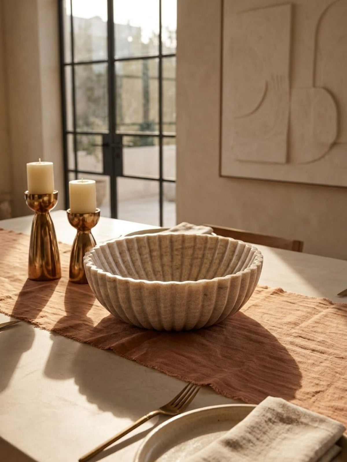 Beige onyx bowl with vertical fluted detailing, styled as a centerpiece on a dining table.