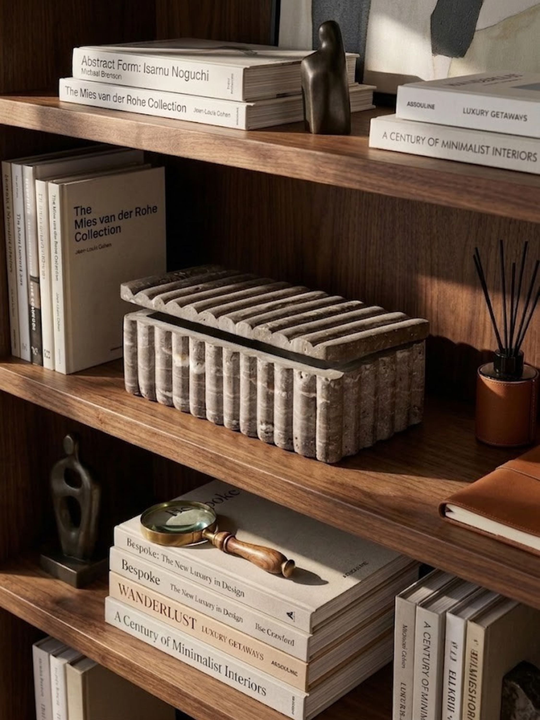 Gray travertine ribbed box styled on a shelf in a home library setting.
