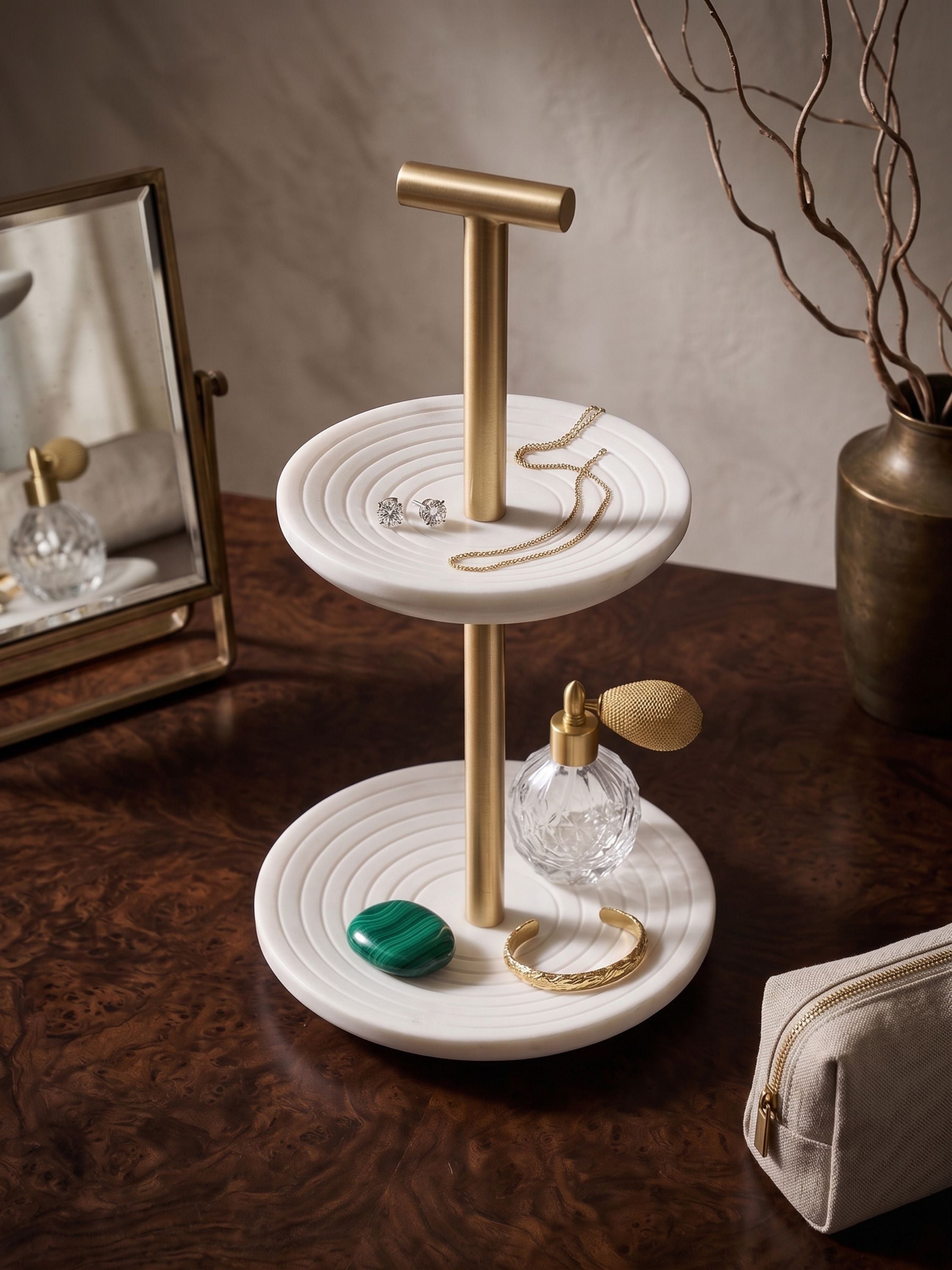 White marble tiered jewelry stand with brass stem, featuring carved circular trays, styled on a vanity with everyday accessories