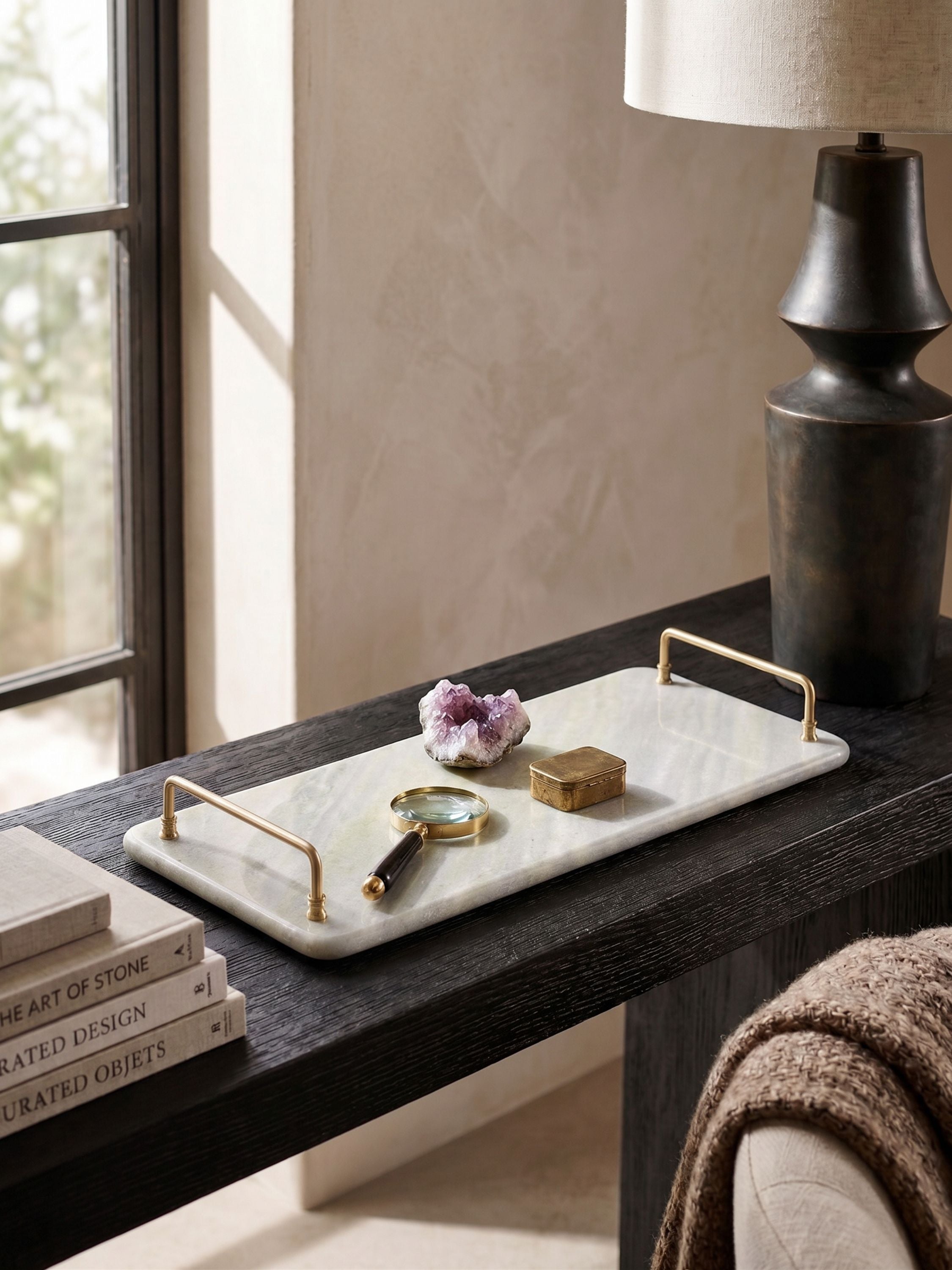 Green onyx decorative tray with brass handles styled on a console table with small objects in a refined interior setting