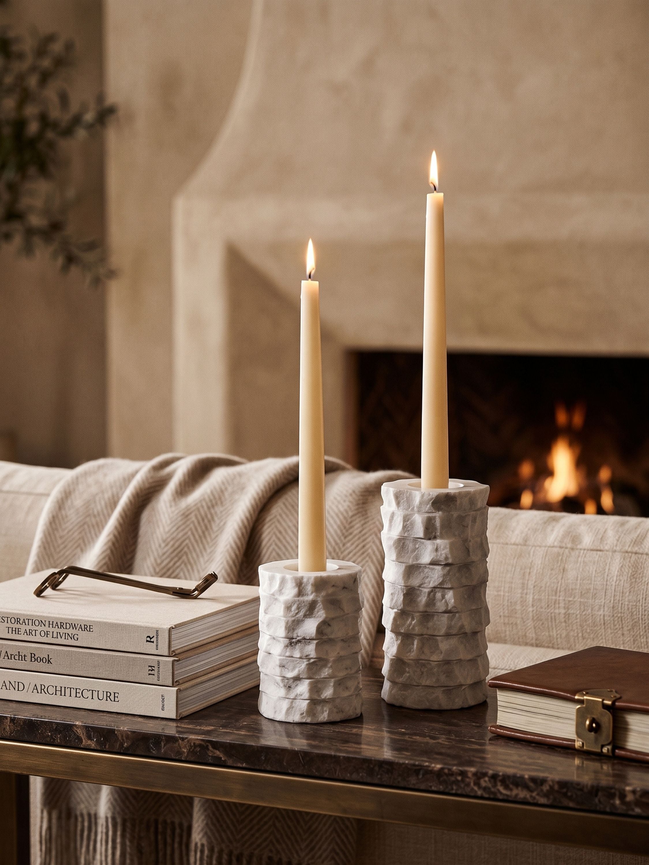 Chiseled marble candle holders with lit taper candles styled on a console table in a warm living room setting
