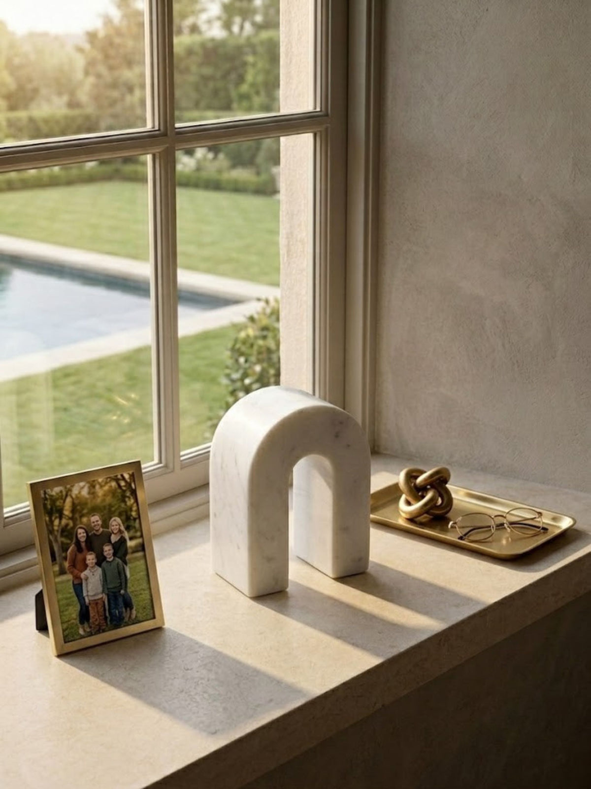 White marble arch object with gray veining, placed on a living room windowsill.