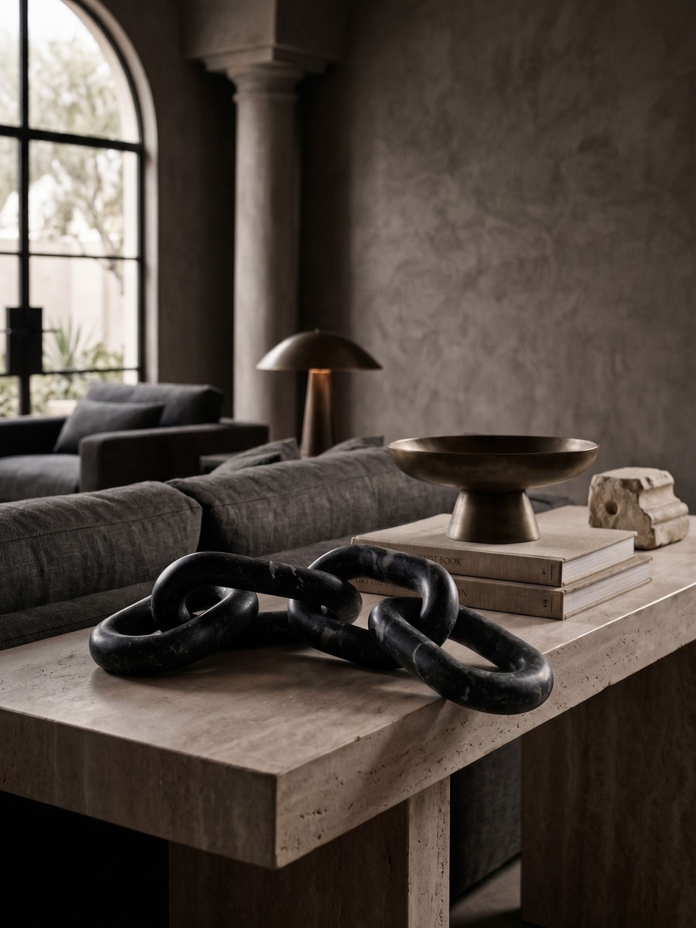Black marble chain link sculpture styled on a console table with books in a moody modern living room