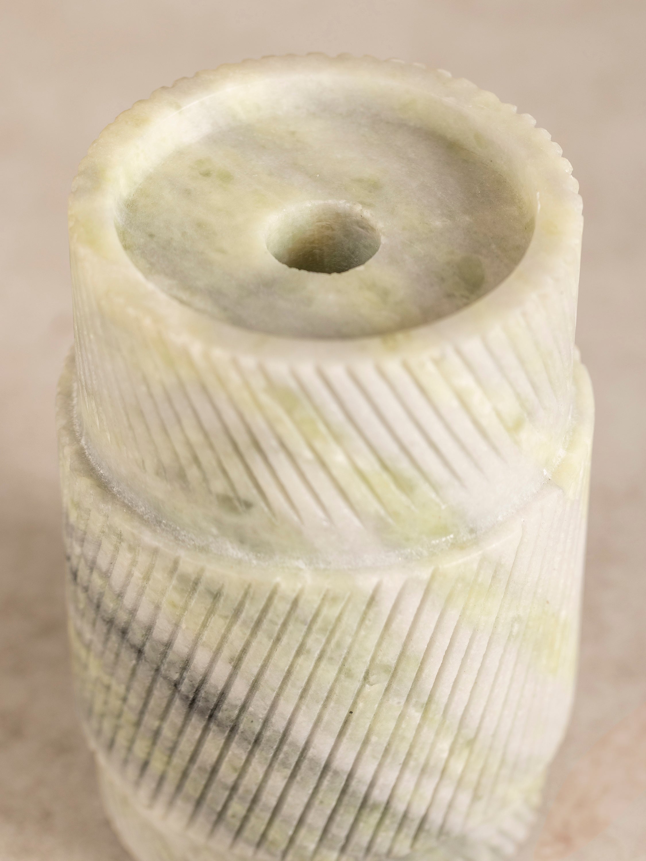 Close-up of carved onyx candle holder base showing ribbed vertical texture and layered green stone veining