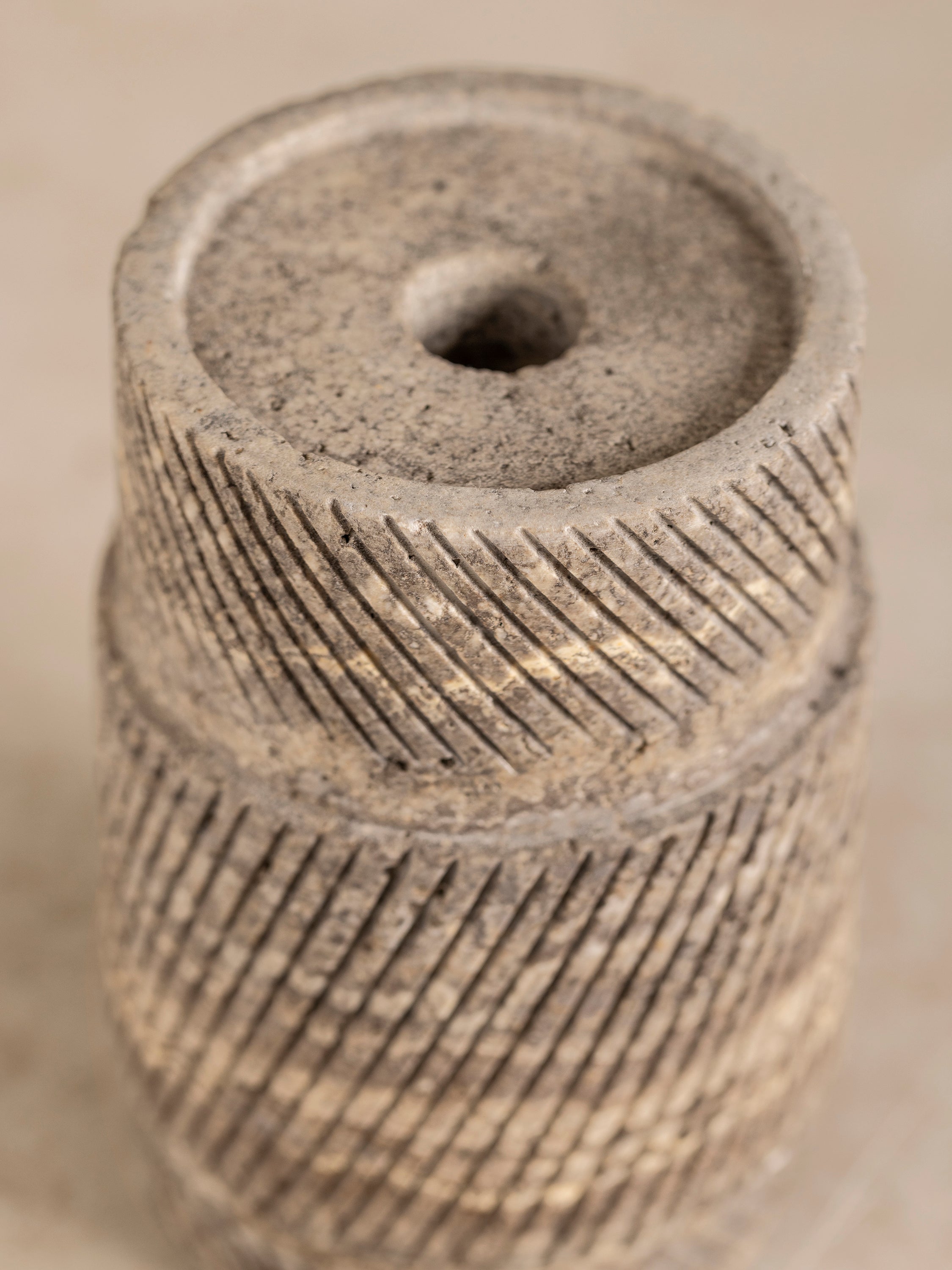 Close-up of travertine candle holder base showing ribbed carved texture and layered brown and beige stone variation