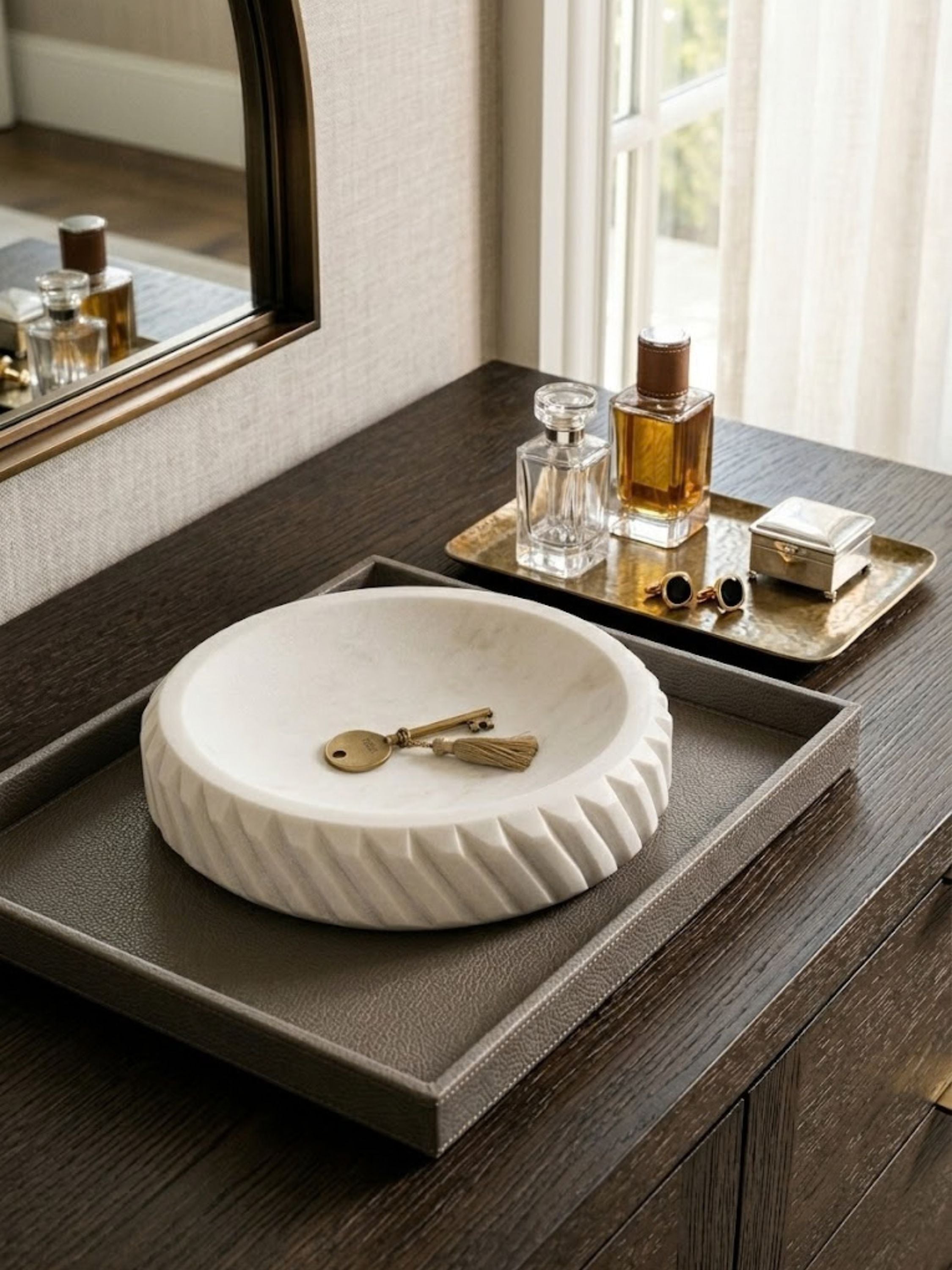 Charlotte marble bowl displayed on a coffee table beside polished stones and floral accents in a living room setting.