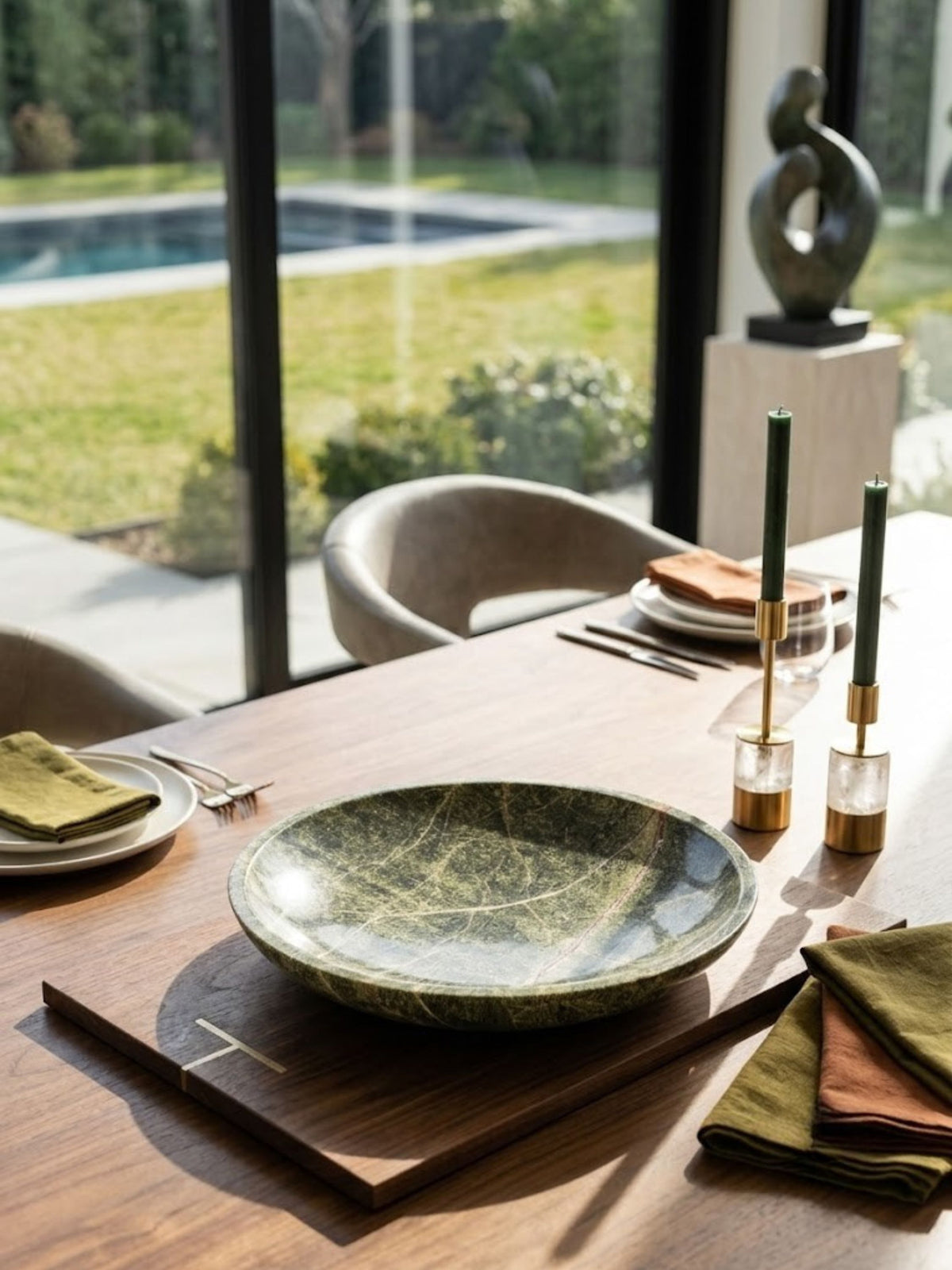 Green marble bowl in forest green tones, styled outdoors near a pool.