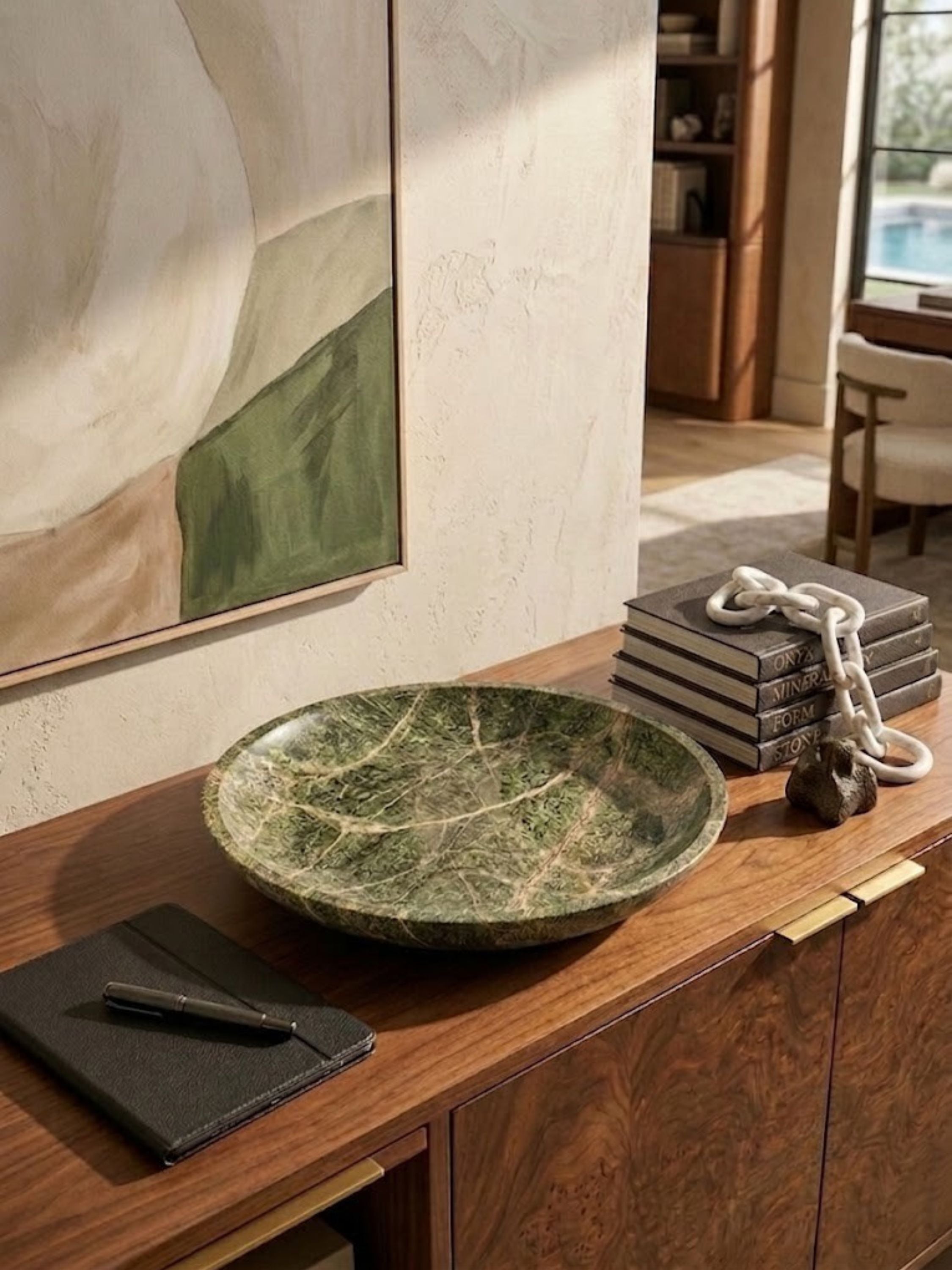 Green marble bowl with a curved base, styled on a credenza.