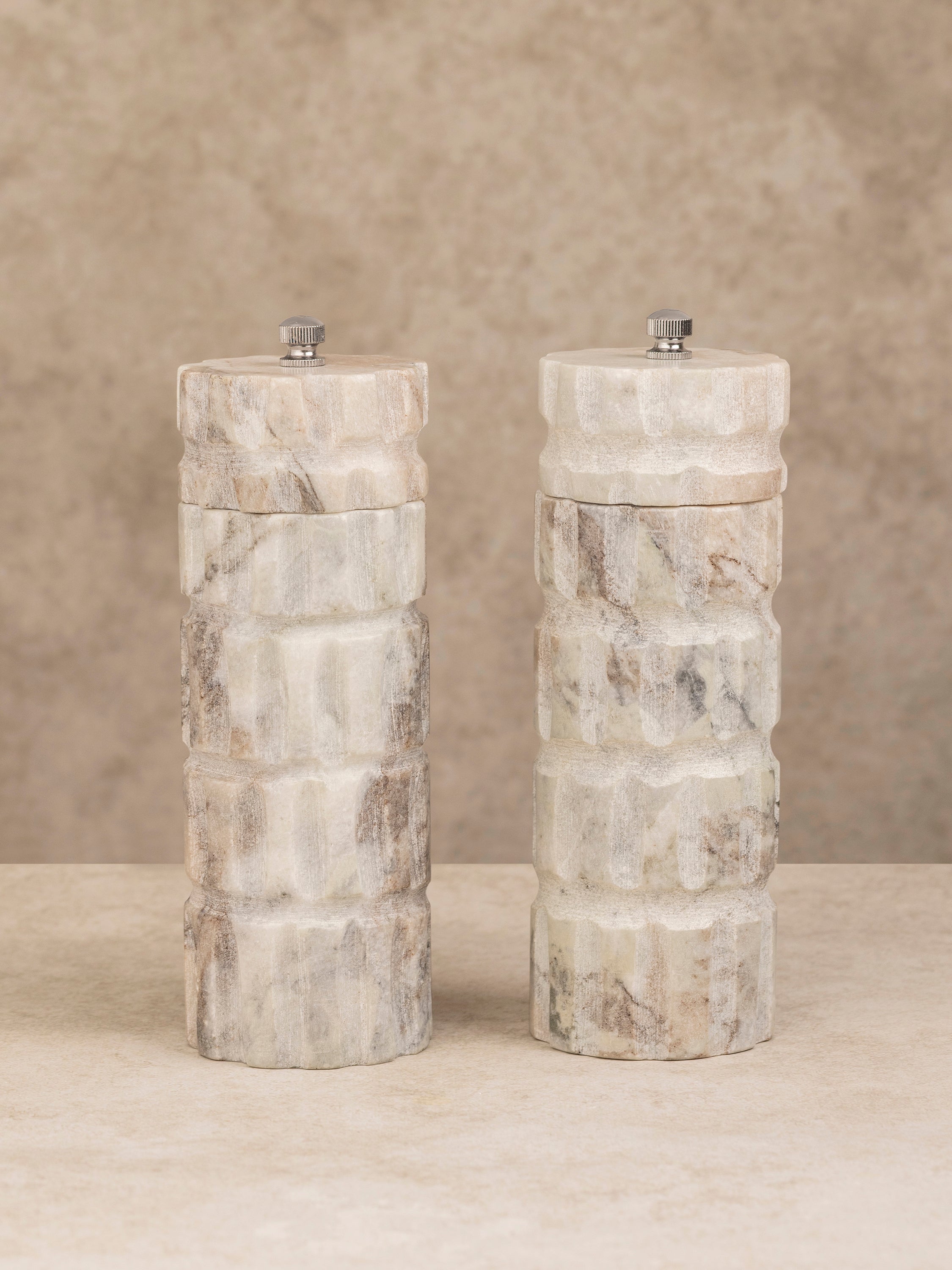 Beatrix salt and pepper mills shown together, highlighting their matching cylindrical marble forms and polished finish.