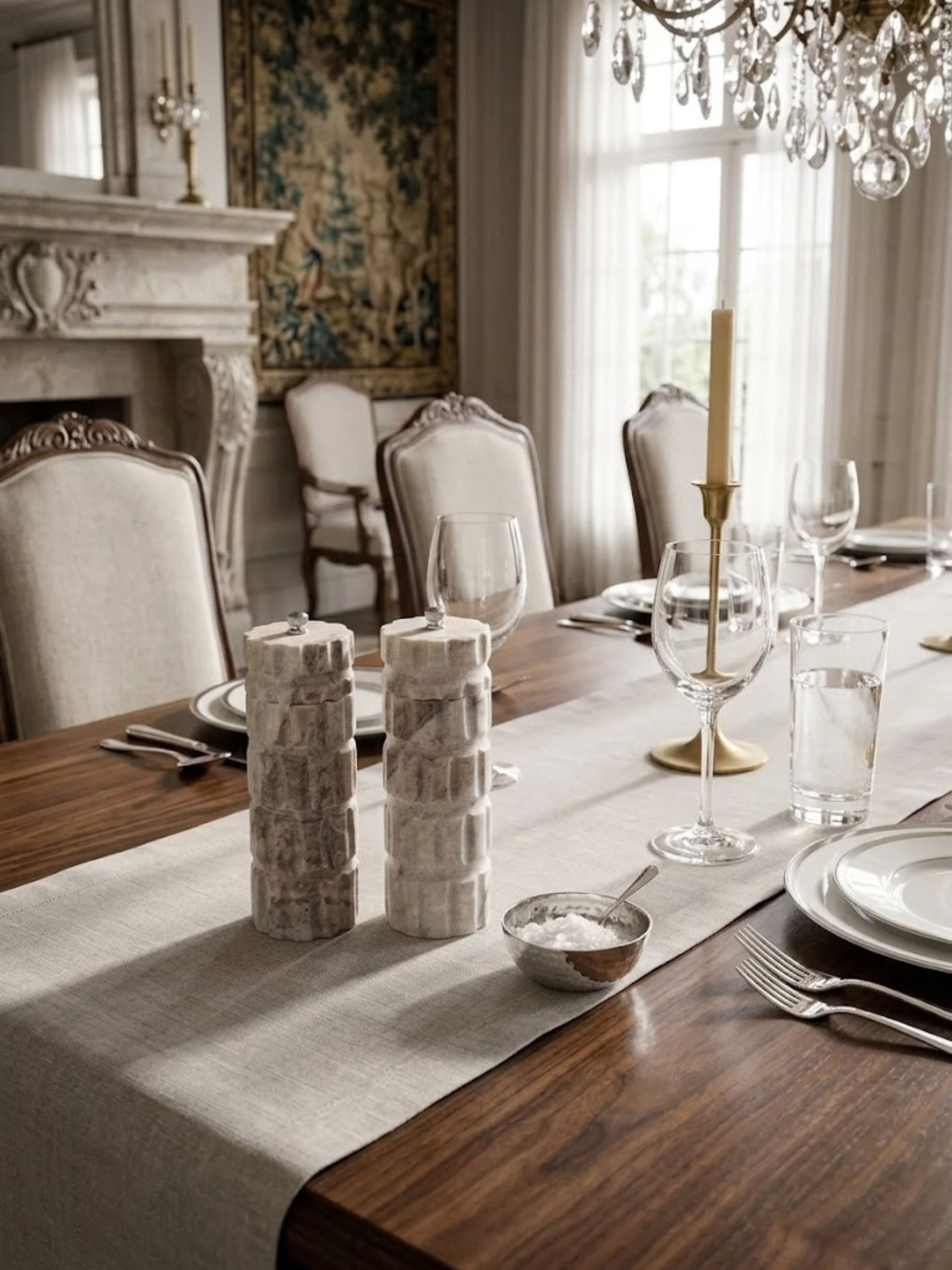 Beatrix marble salt and pepper mills arranged on a linen table runner, highlighting their carved marble detailing.