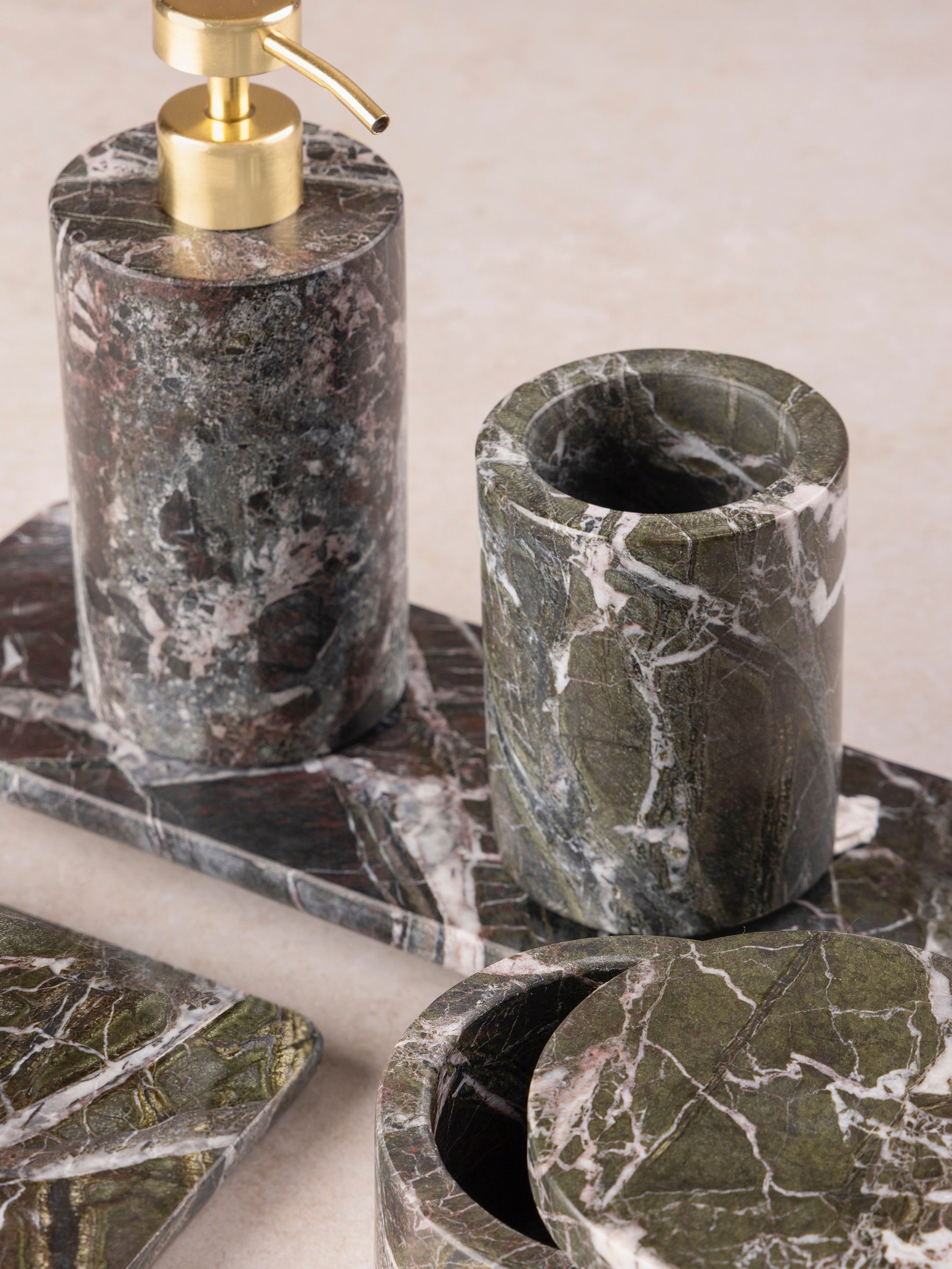 Close-up of Jardin Verde Levanto bath set showing brass soap pump, green marble dispenser body, and coordinating accessories