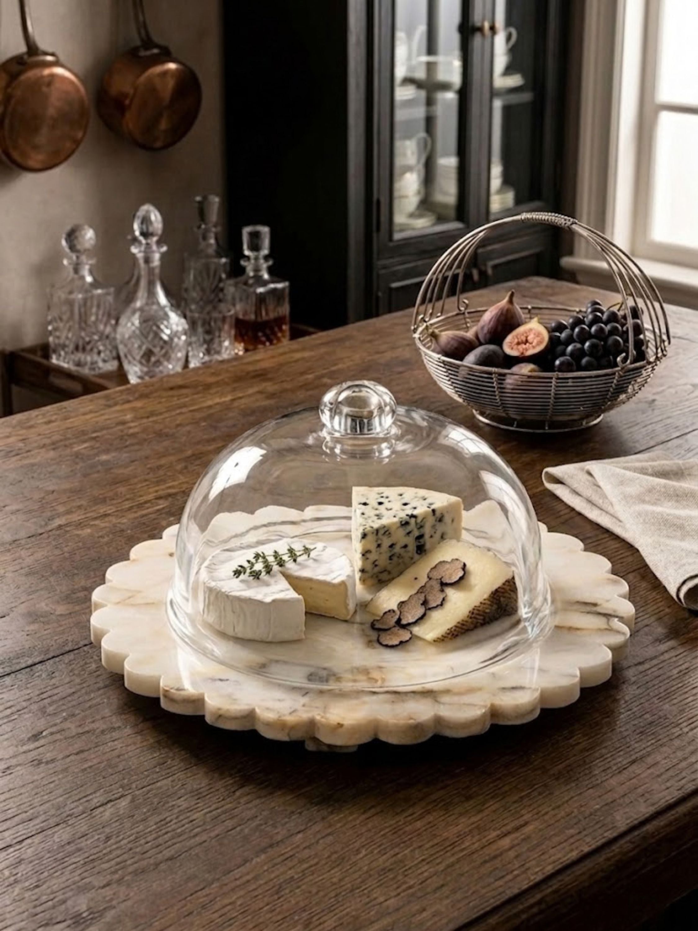 Kismet marble cloche board styled as an elegant cheese presentation piece, featuring a scalloped marble base and clear glass dome for refined entertaining.