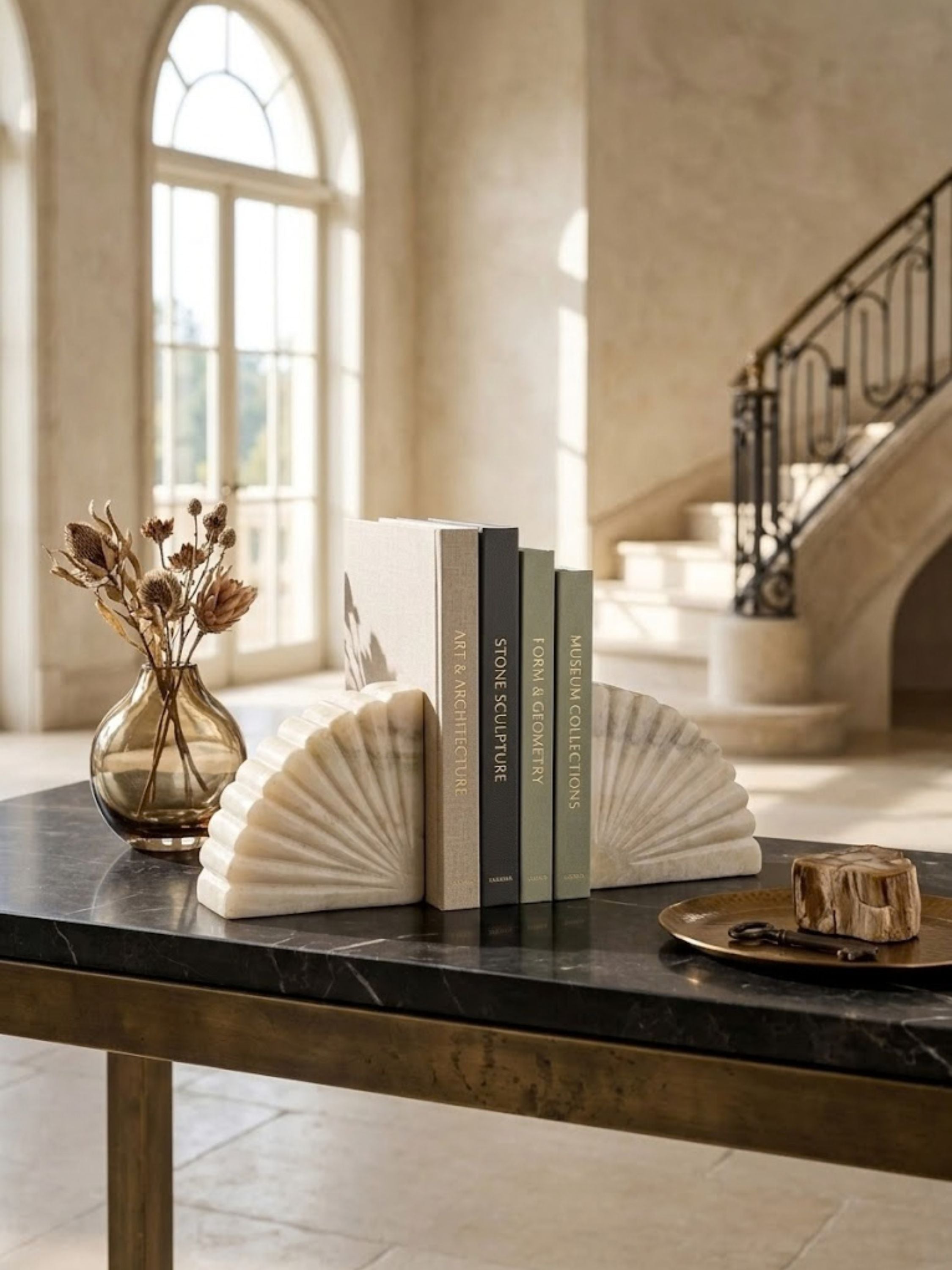 Emrys onyx bookends arranged on a console table with design books, showing their carved stone detailing.