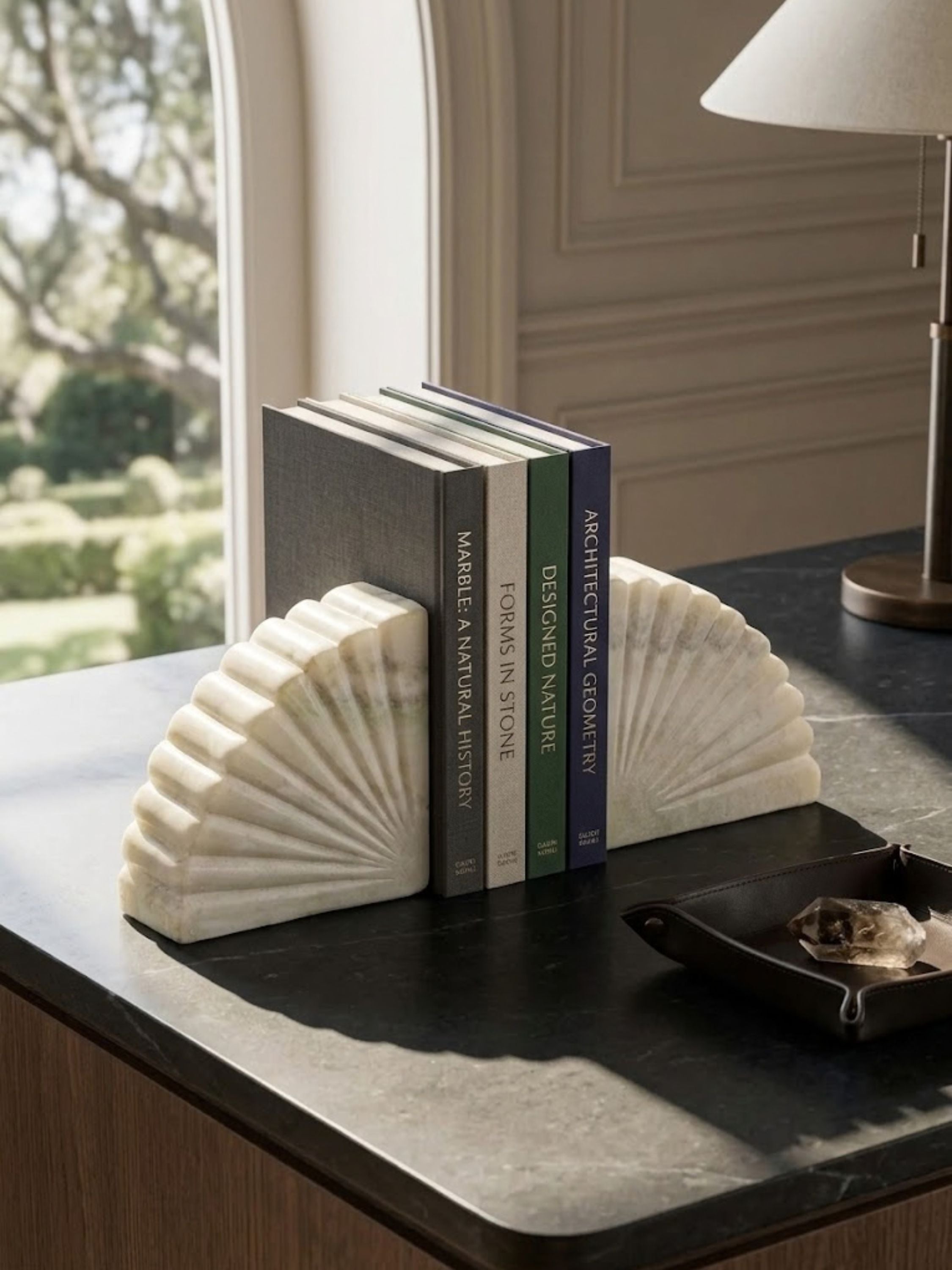 Emrys onyx bookends displayed on a dark stone surface with art and architecture volumes, highlighting their sculptural geometry.