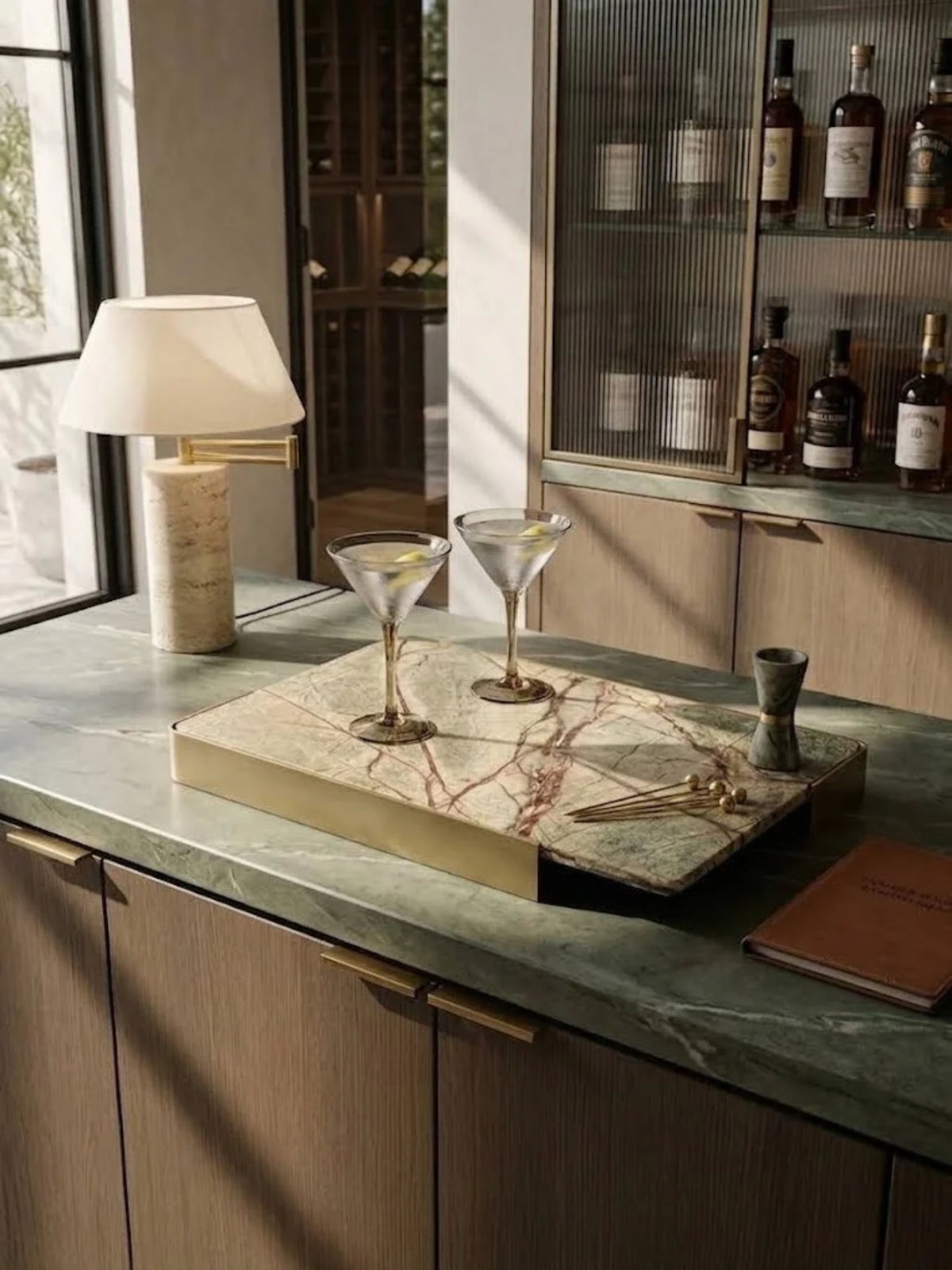Normandy onyx marble tray with brushed gold handles, holding martini glasses at a home bar.