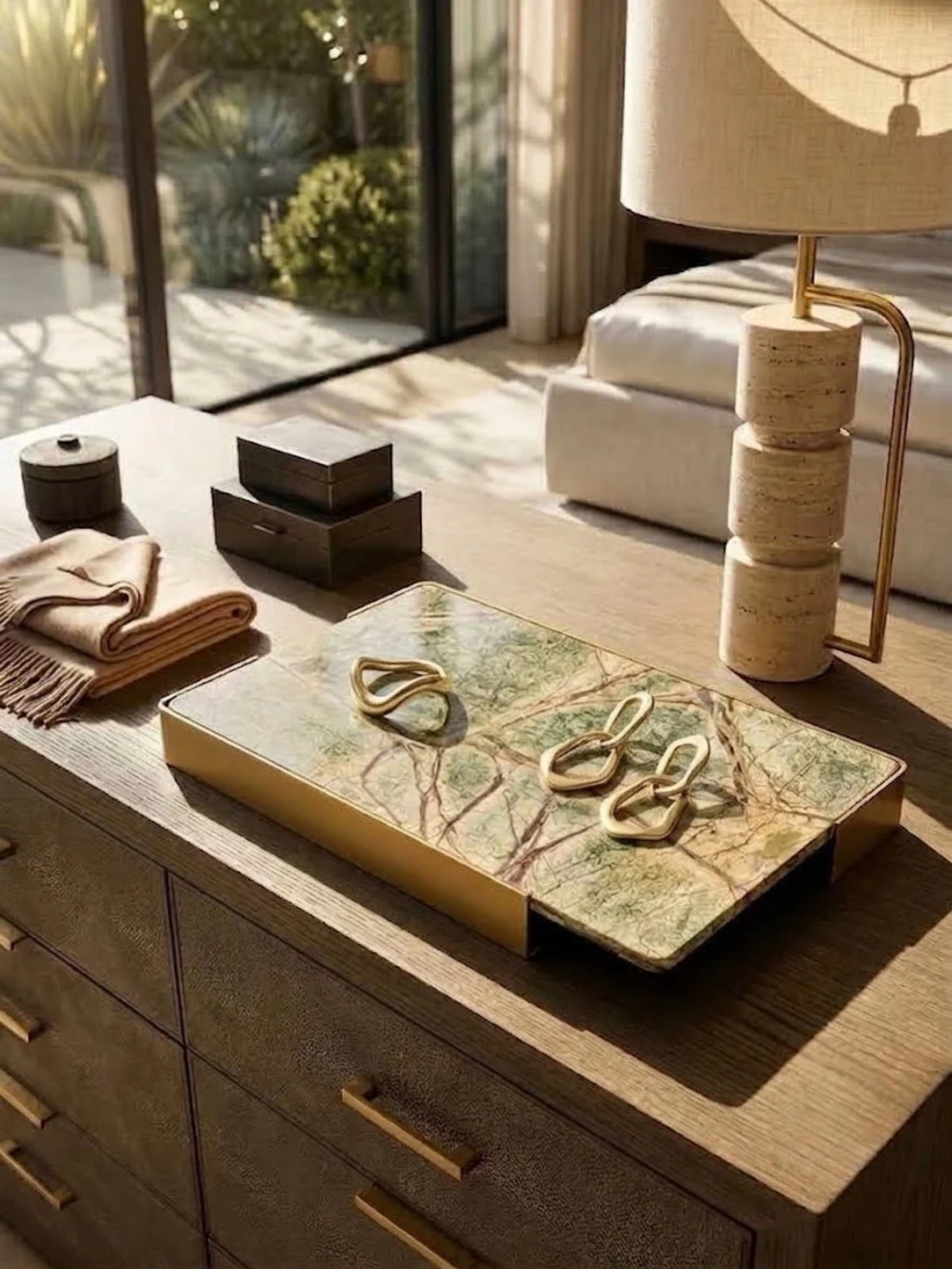Normandy onyx marble tray with brushed gold handles, holding jewelry and glasses on a dressing table.
