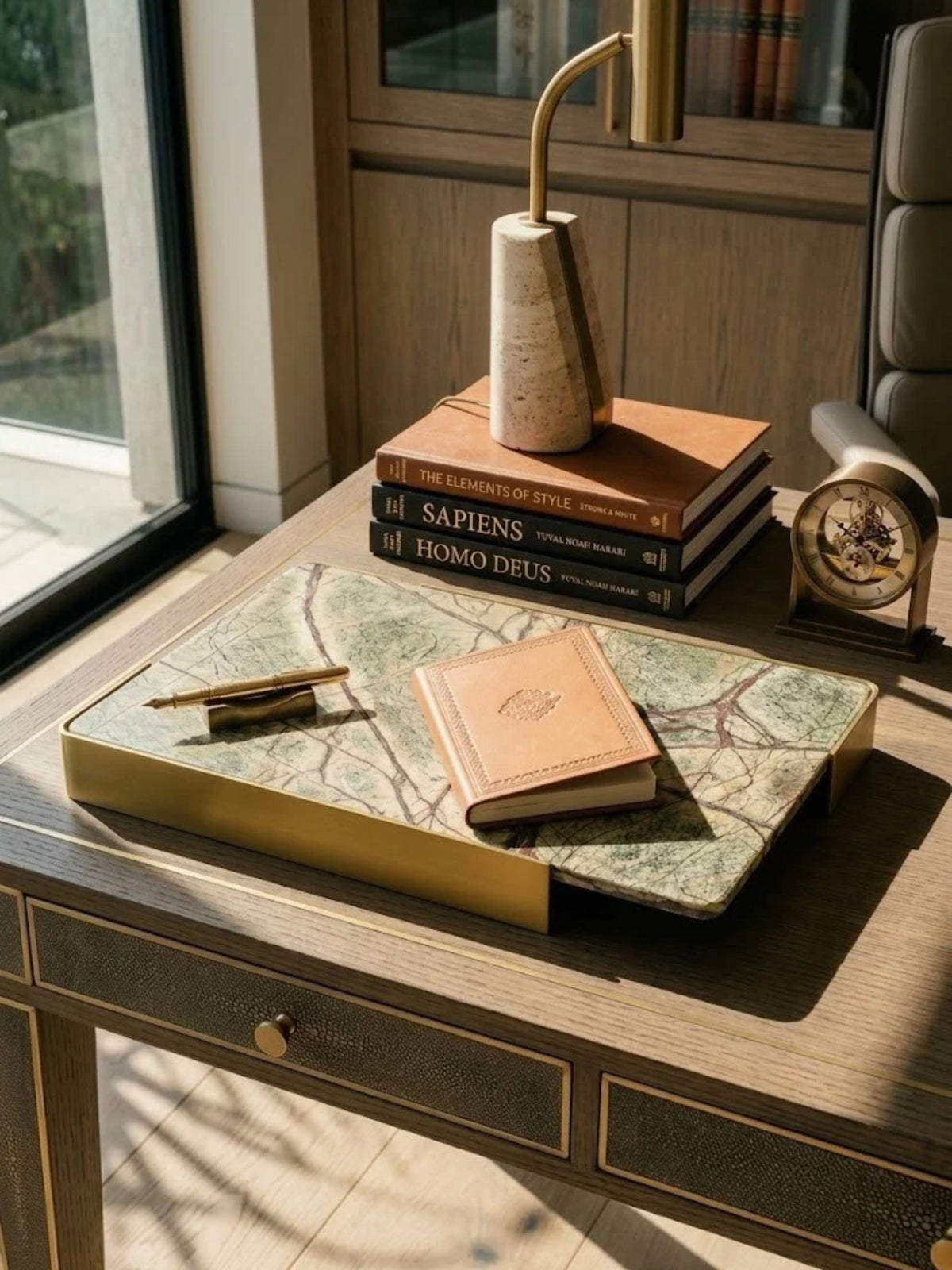 Normandy onyx marble tray with brushed gold handles, holding books and a pen on a home office desk.
