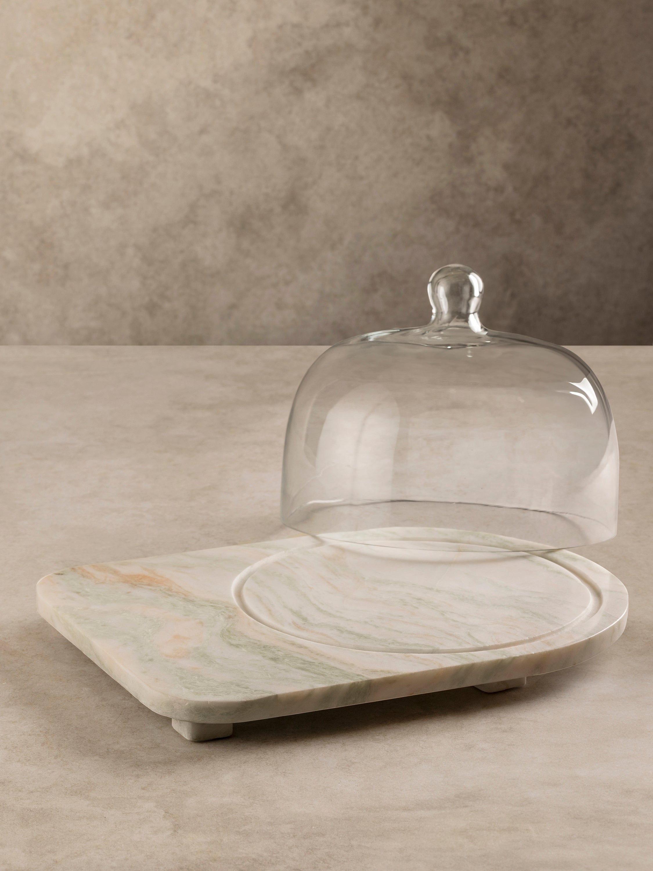 Moonlight onyx cloche board shown with the glass dome lifted, revealing the naturally veined onyx surface and rounded form.