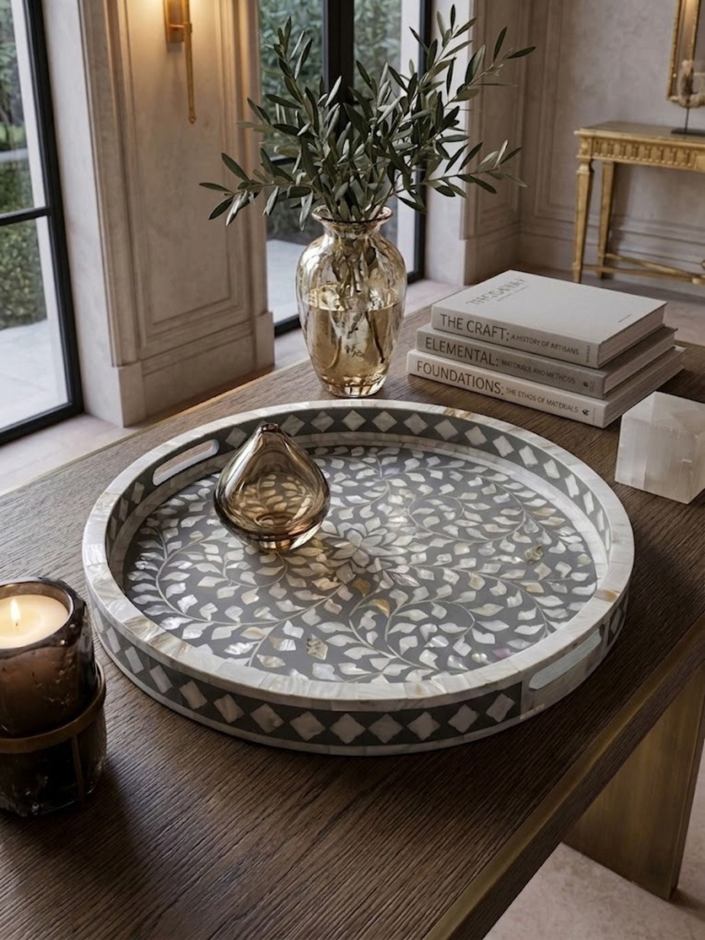 Mother of pearl inlay round tray with a grey ground, styled on an entryway console.