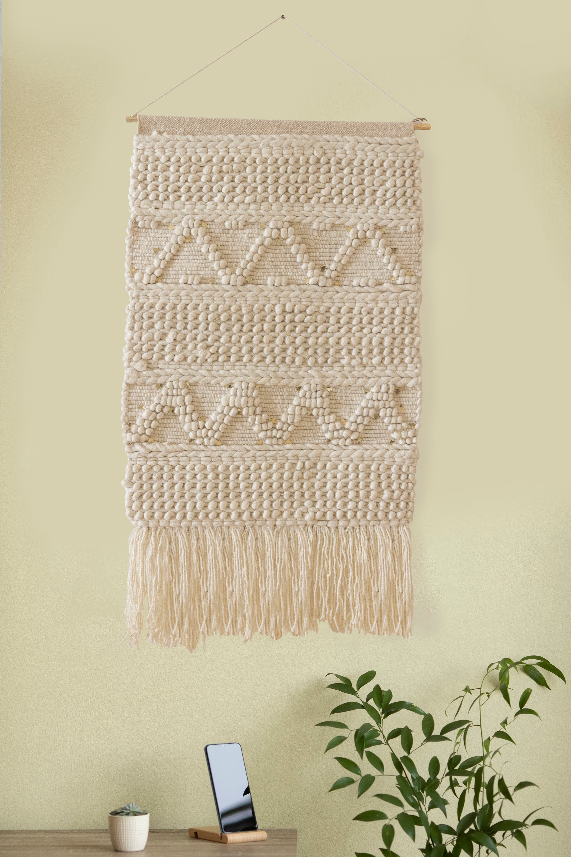 Minimalist handwoven wall tapestry in natural ivory tones with intricate textured details and fringe