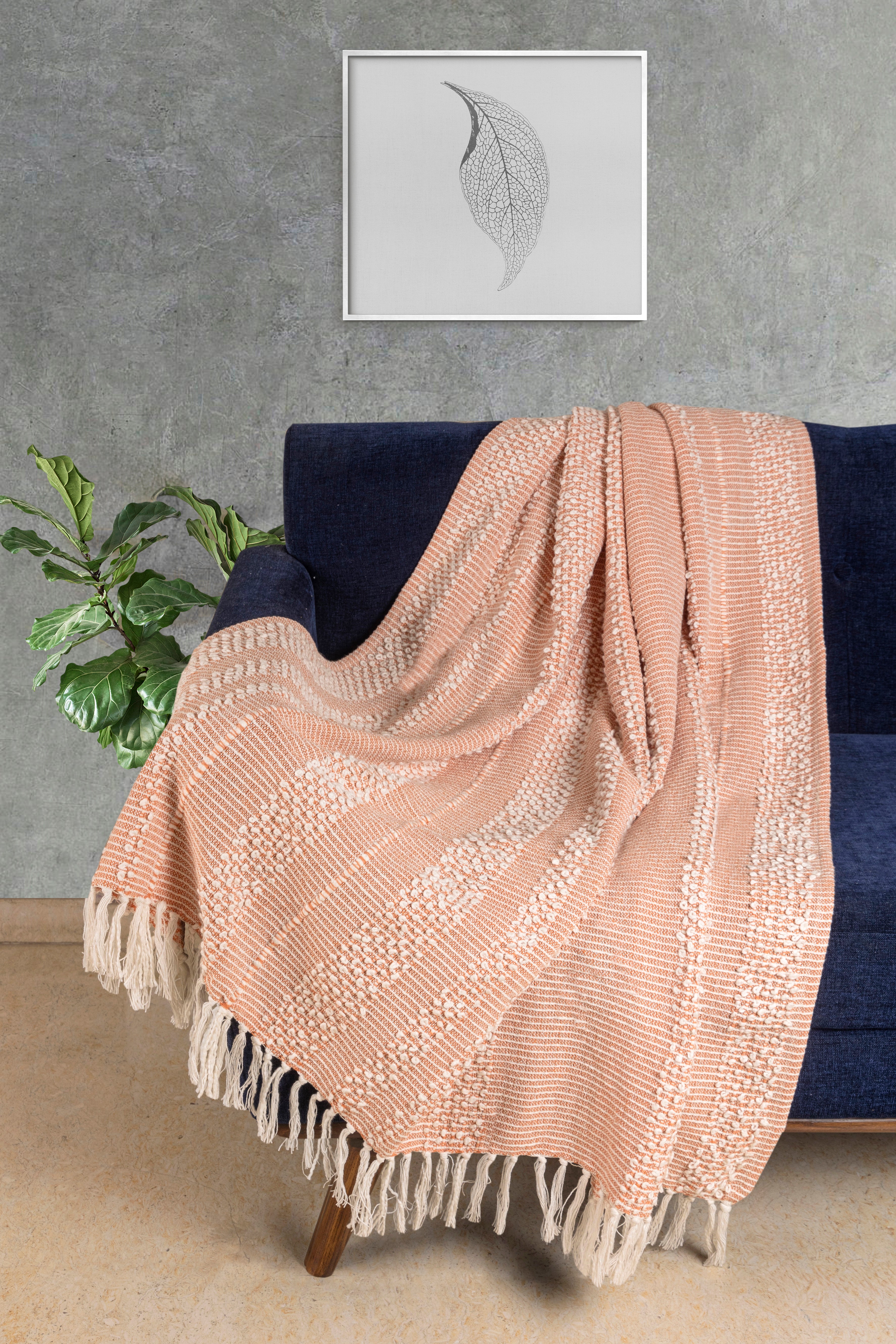 Handwoven natural cotton throw featuring a subtle striped pattern in warm peach tones, ideal for layering on sofas or beds