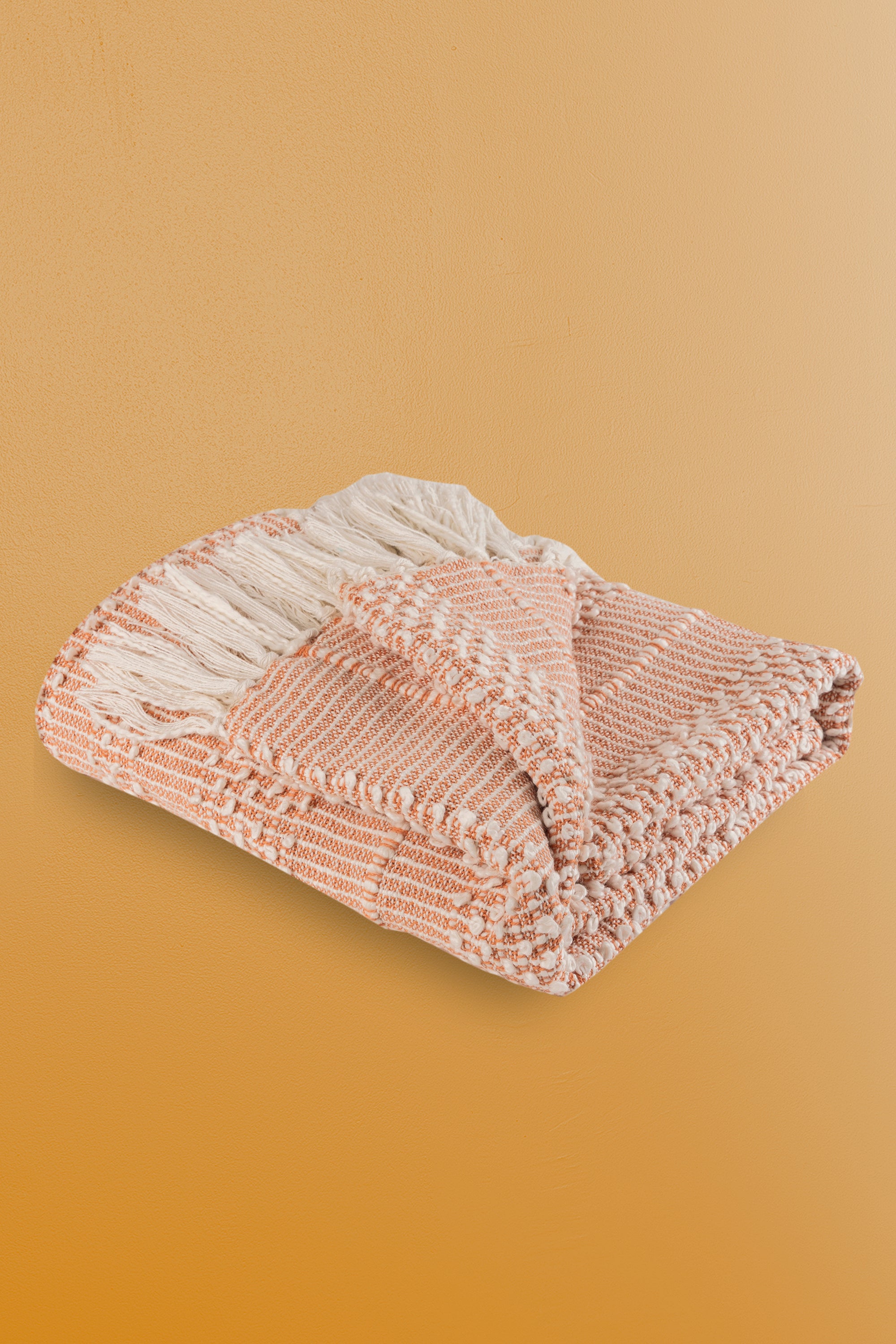 Lightweight and breathable peach-toned throw blanket with intricate woven details and elegant white tassels