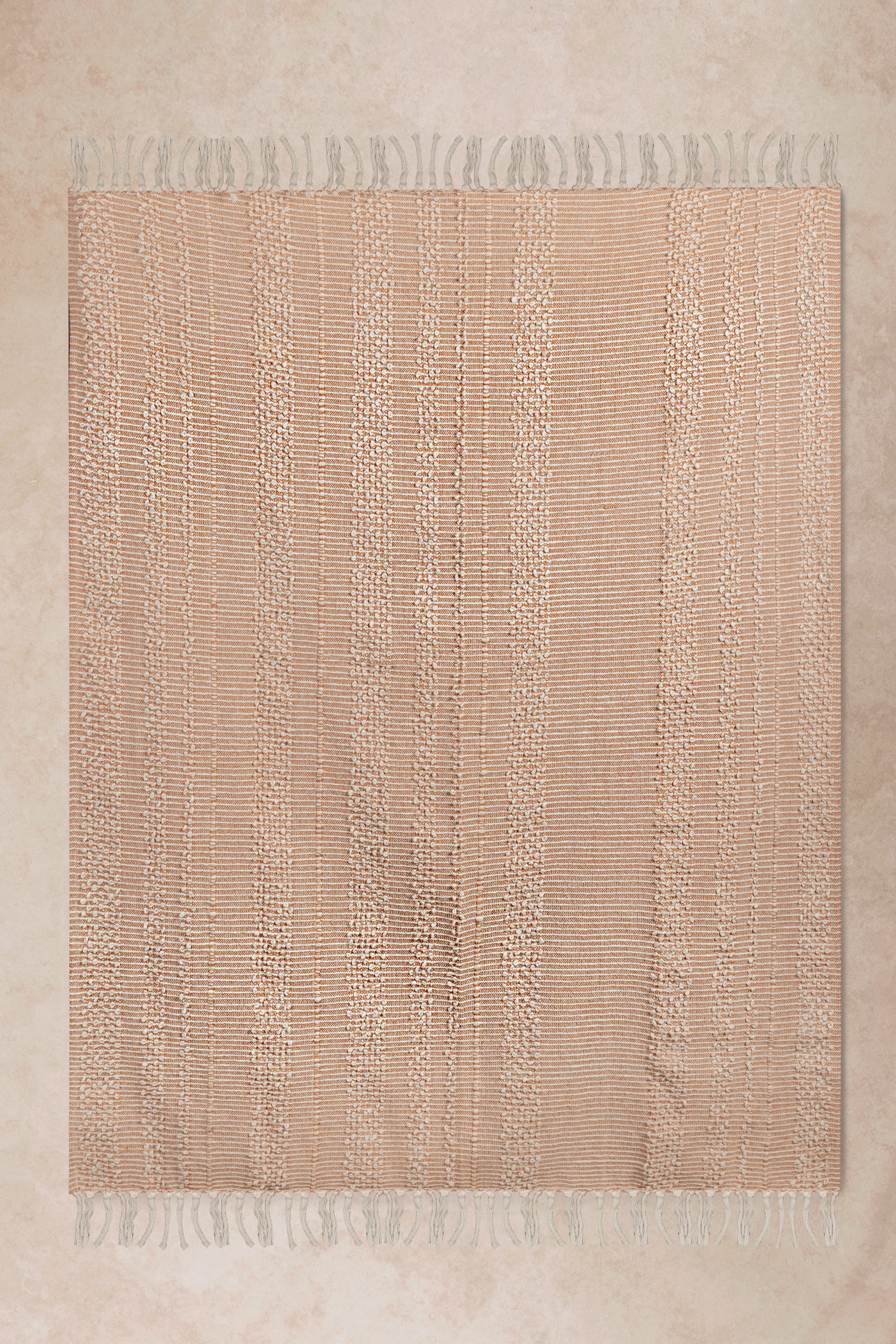 Soft peach pink striped cotton throw blanket with delicate woven texture and tassel fringe, perfect for cozy home decor
