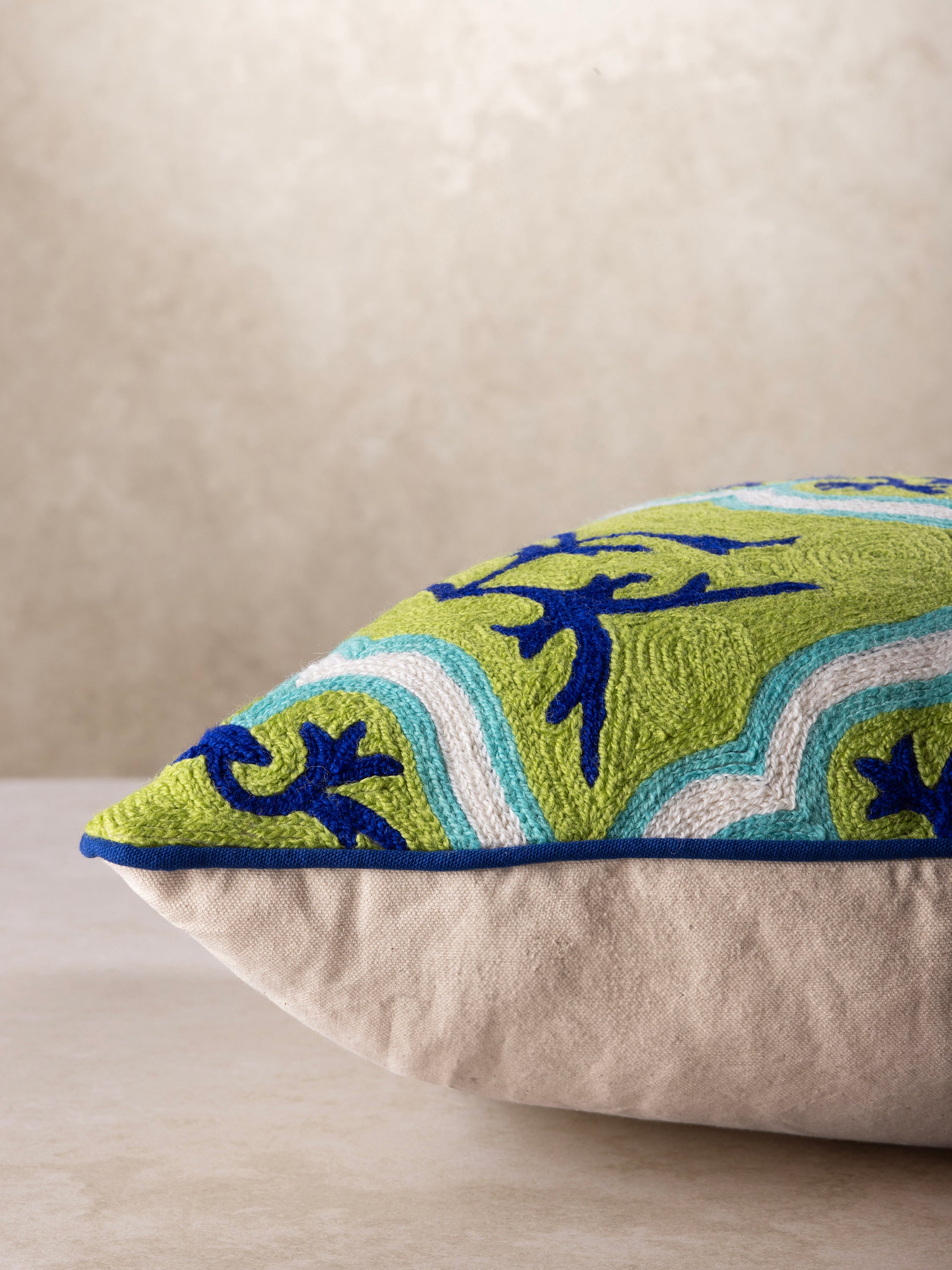 Boho-chic embroidered pillow with a bold blue and green motif, blending traditional elegance with modern style