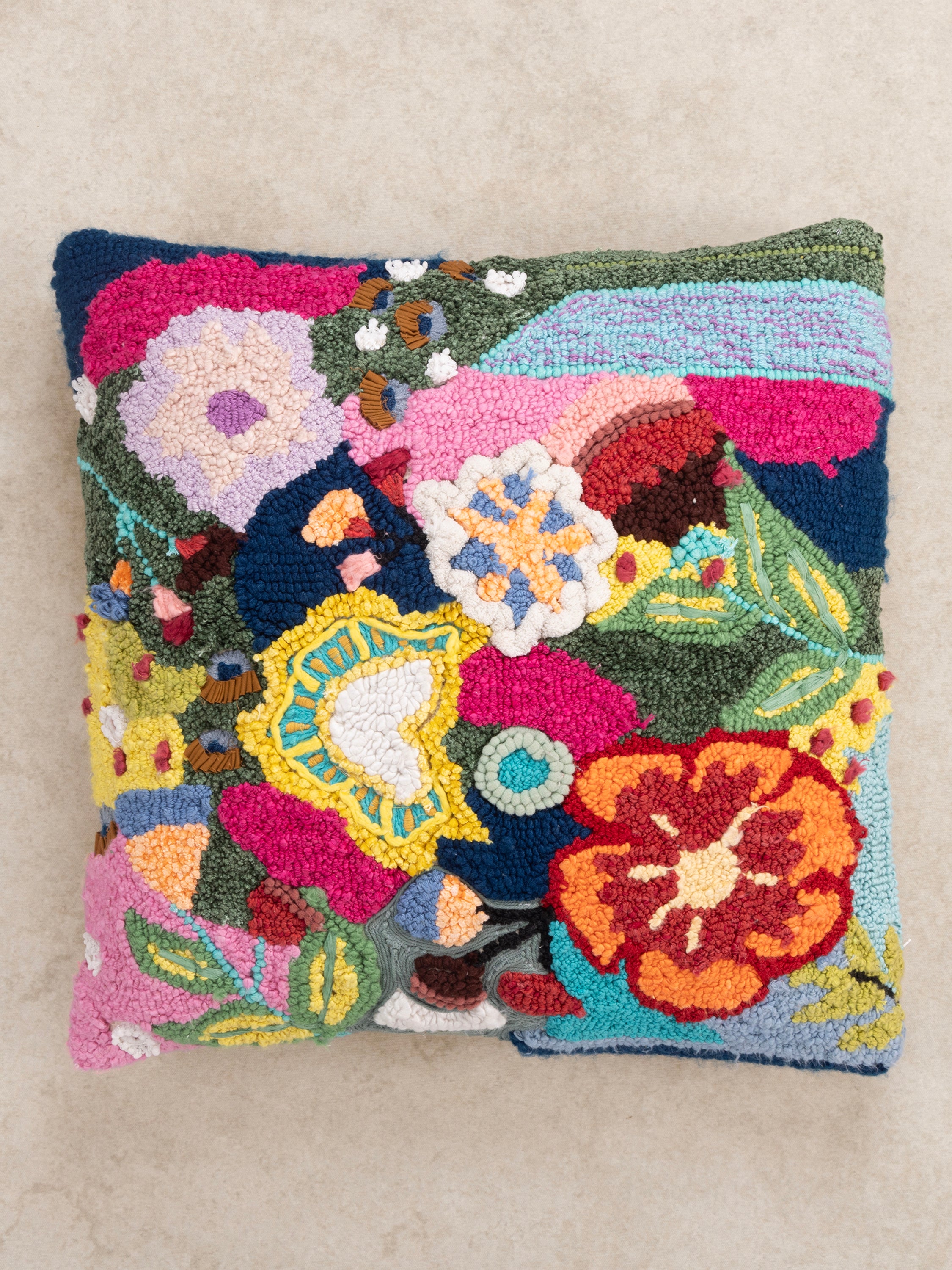 Handcrafted punch-needle cushion with an artistic mix of bright flowers and textured embroidery, ideal for boho and eclectic decor