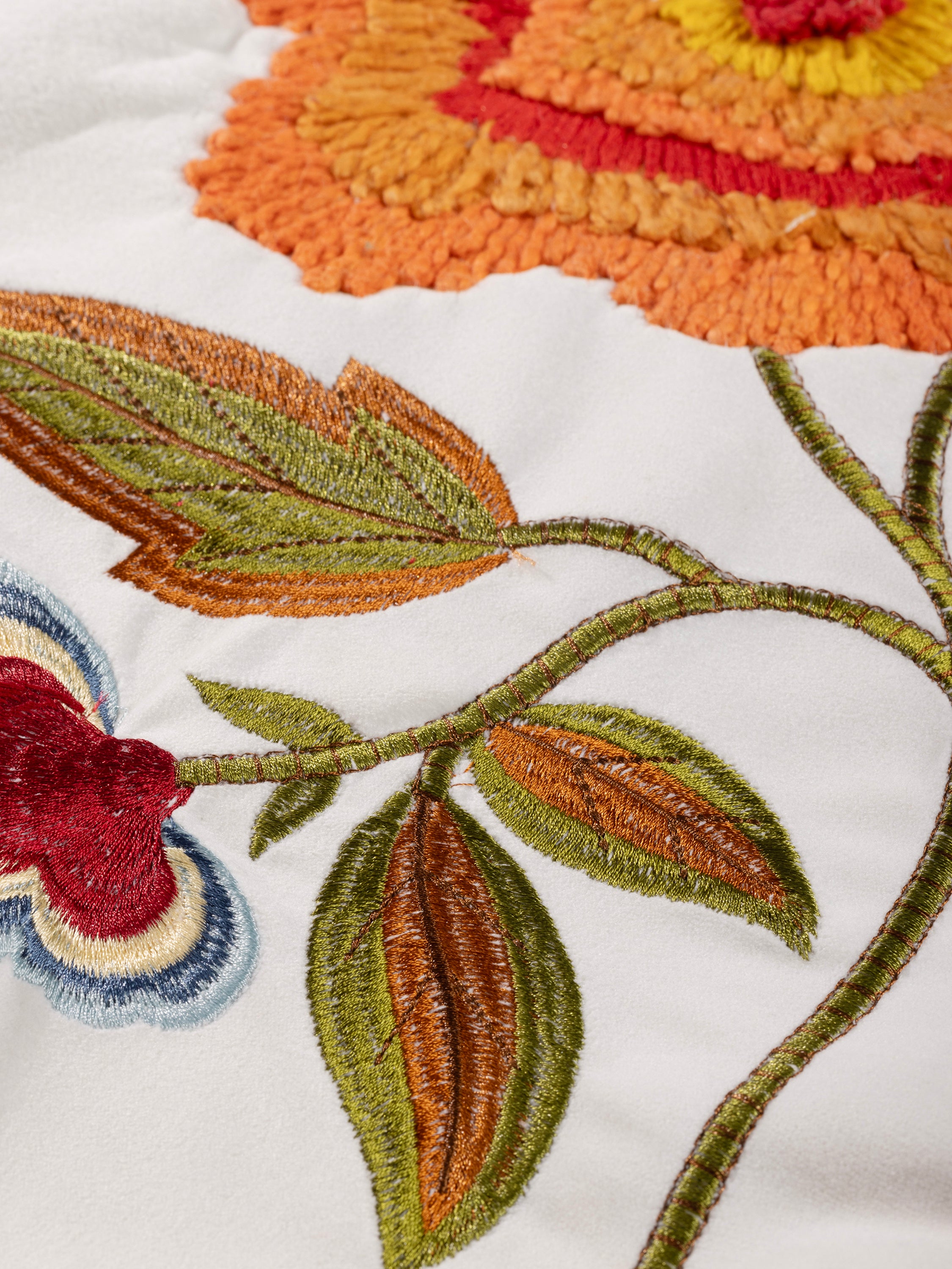 Beautifully embroidered pillow with a striking botanical design, featuring detailed flowers and a graceful bird, adding charm to any room