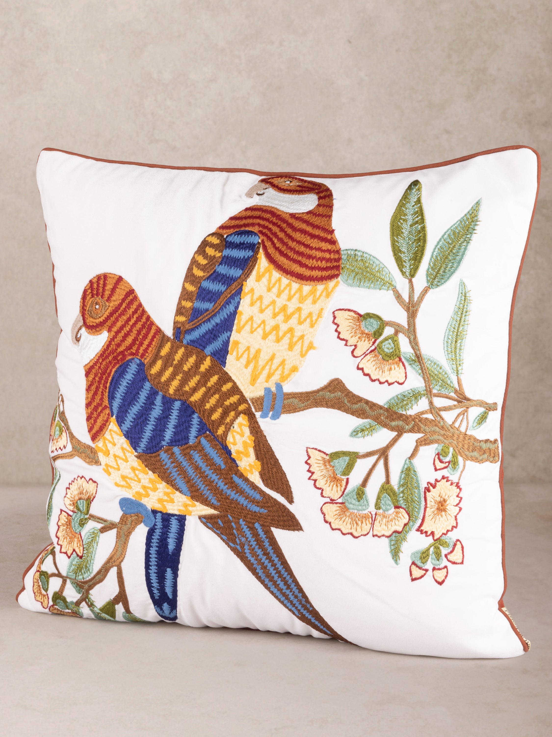 Elegant embroidered throw pillow featuring two colorful birds perched on a branch with floral details, perfect for adding a nature-inspired touch to any space