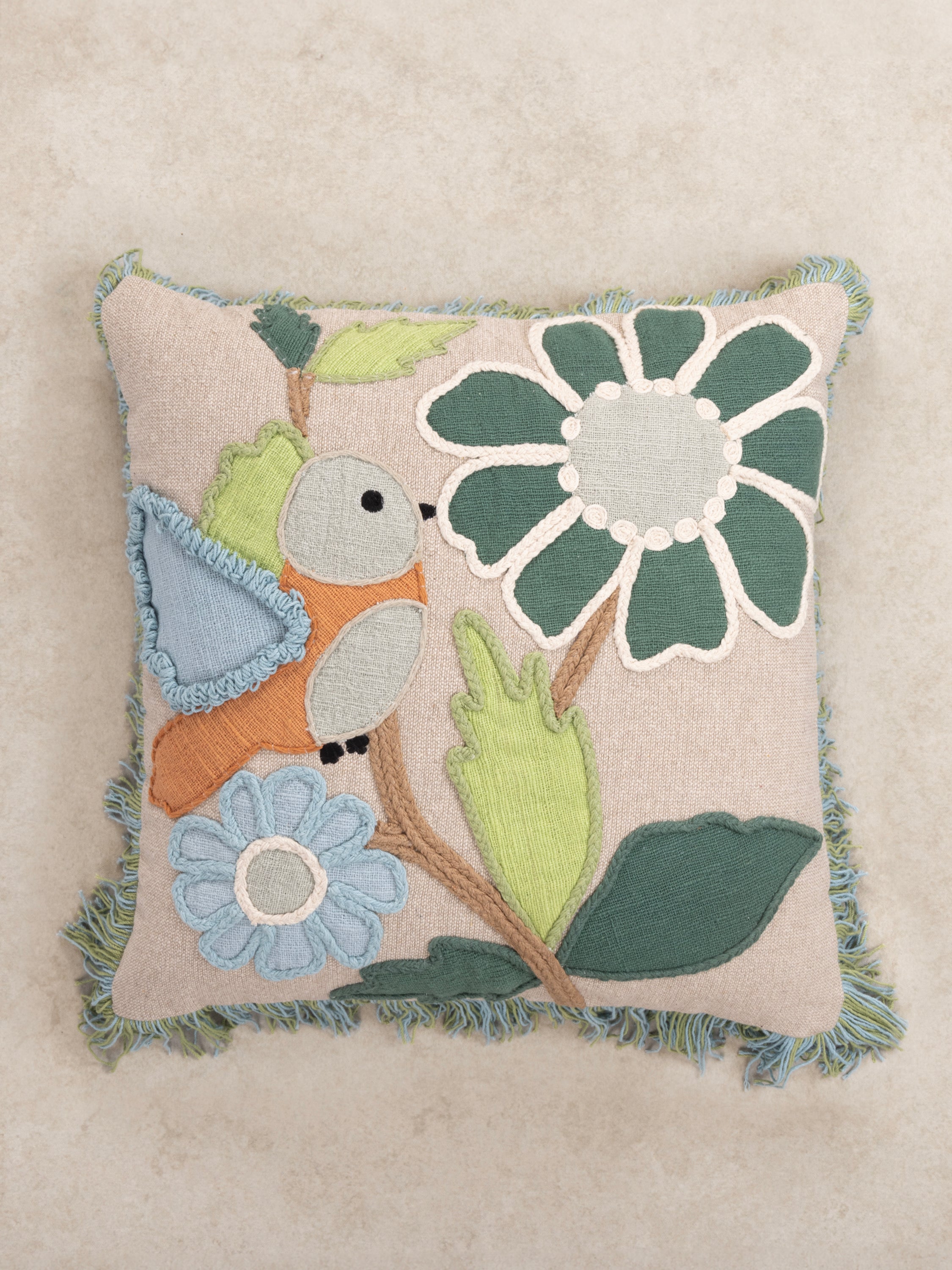 Boho-Inspired Appliqué Bird Pillow with Botanical Stitching – A cozy accent cushion with a playful bird, vibrant flowers, and leaf motifs, crafted with detailed embroidery on a neutral beige fabric