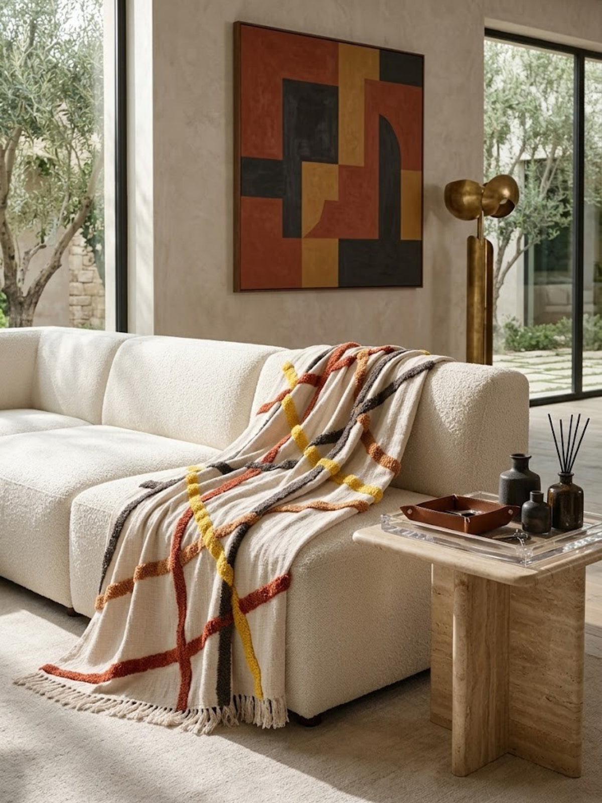 Tashi ivory cotton throw with crossing tufted lines, draped over a cream sofa in a living room.