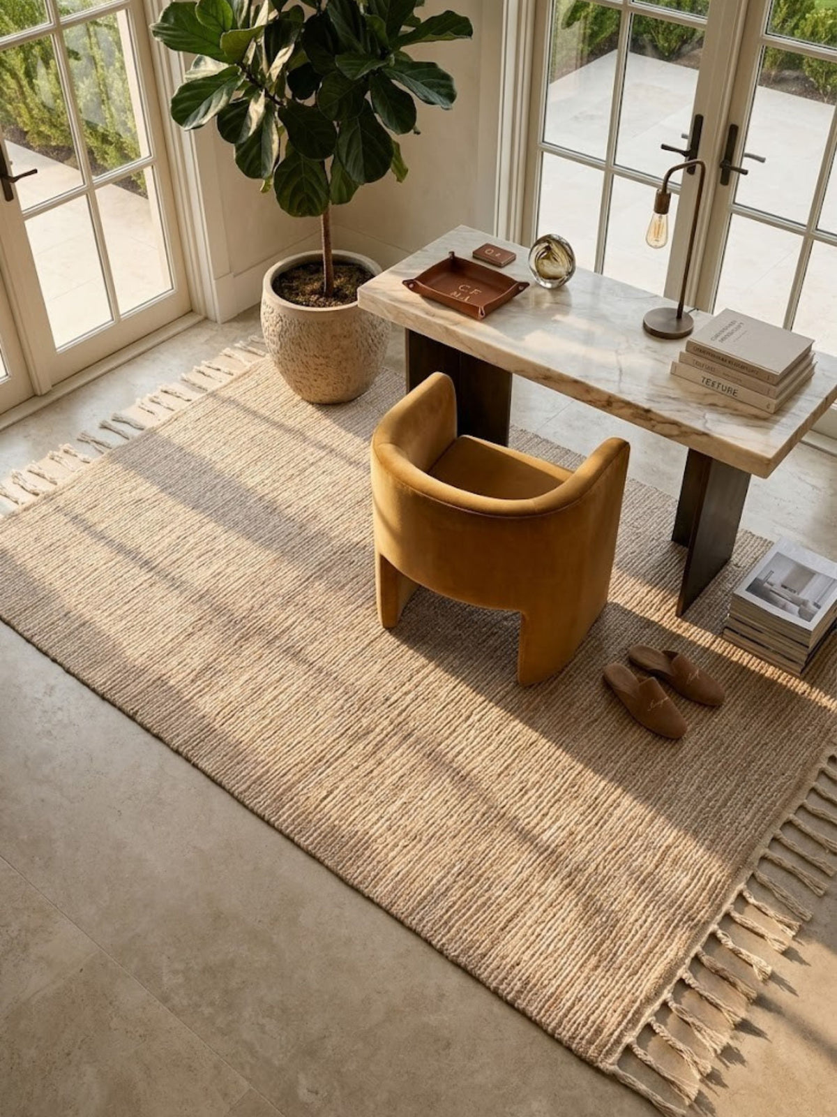 Off-white jute, wool, and cotton rug styled in an entryway, twisted cotton fringe visible at the edge.
