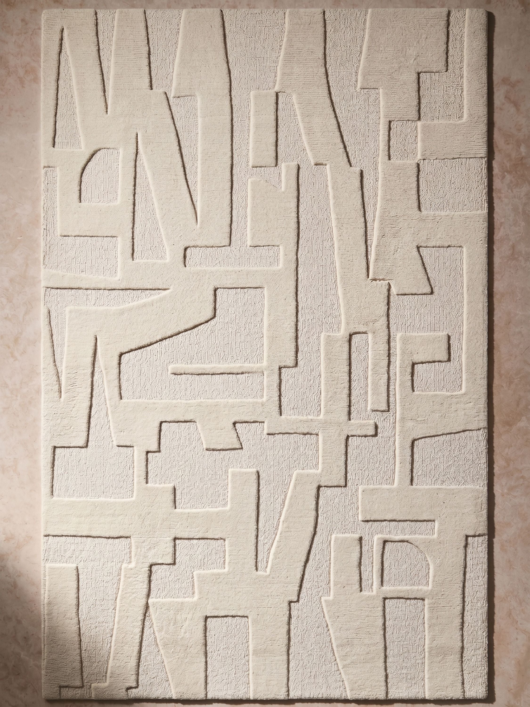 Ivory wool area rug with sculpted abstract pattern and raised texture in a monochrome neutral tone