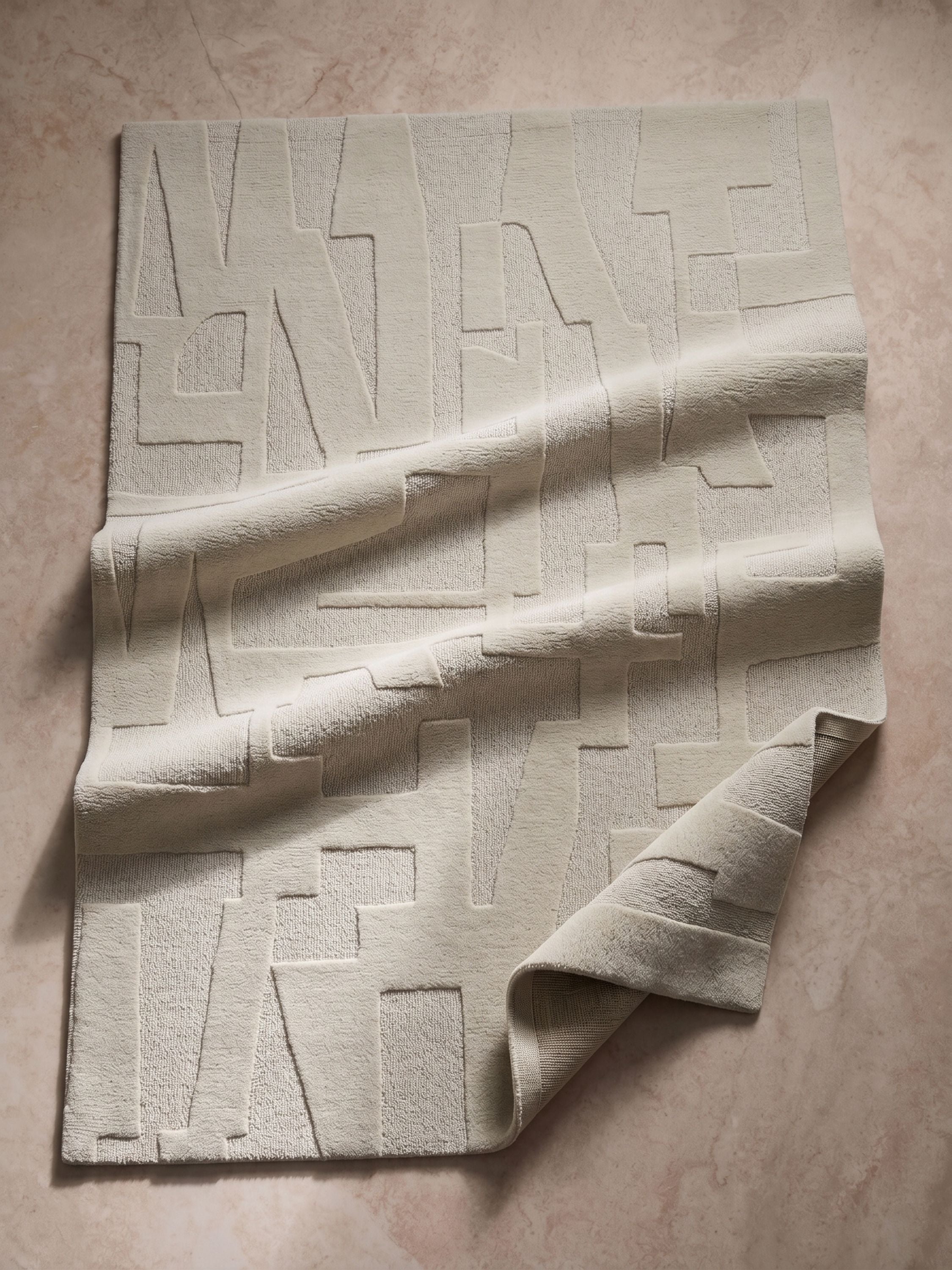 Close-up of ivory wool rug showing raised sculpted abstract pattern and soft textured surface