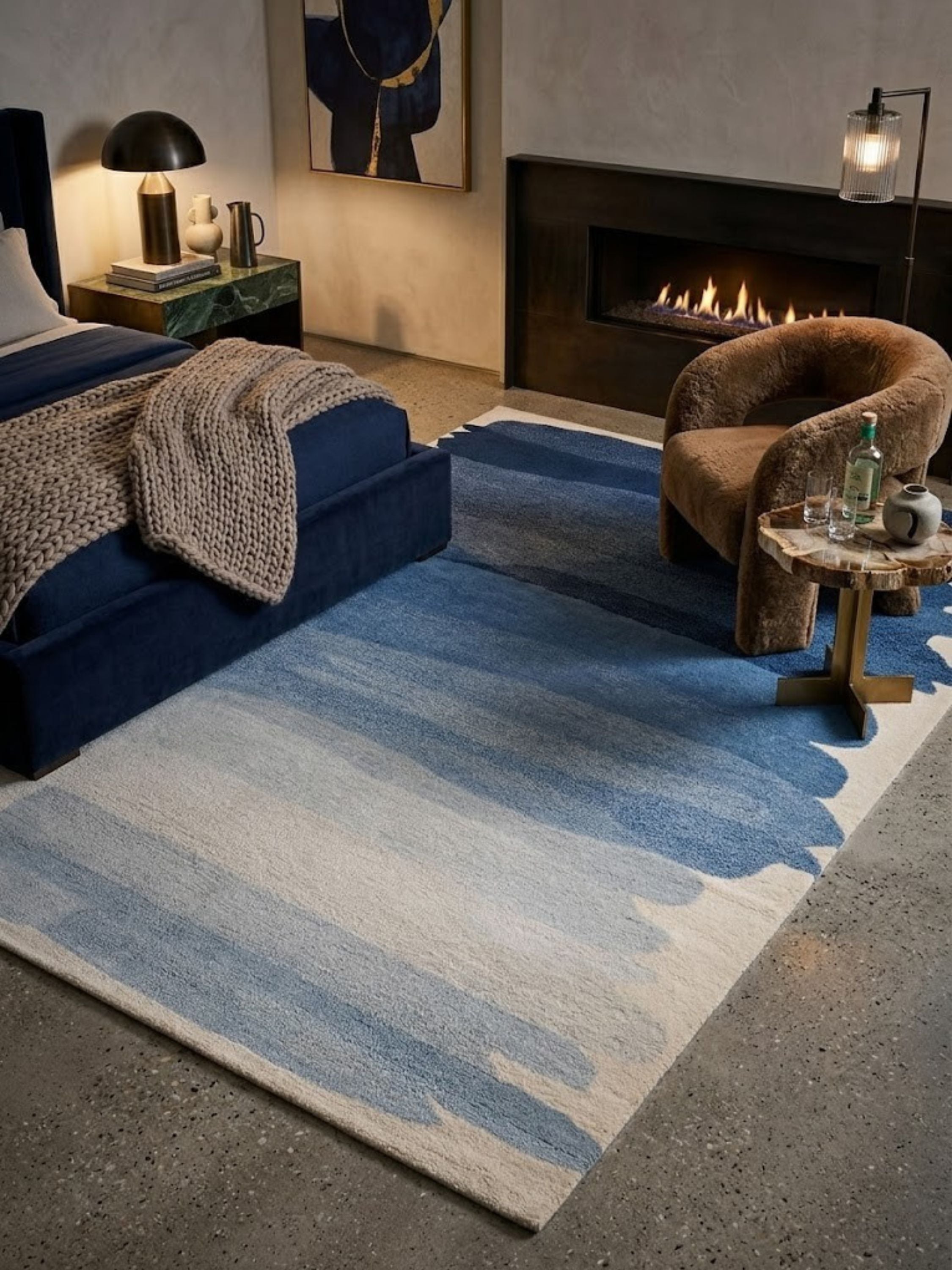 Navy-to-ivory wool rug, tonal color band, placed in a bedroom beside a fireplace nook and accent chair.