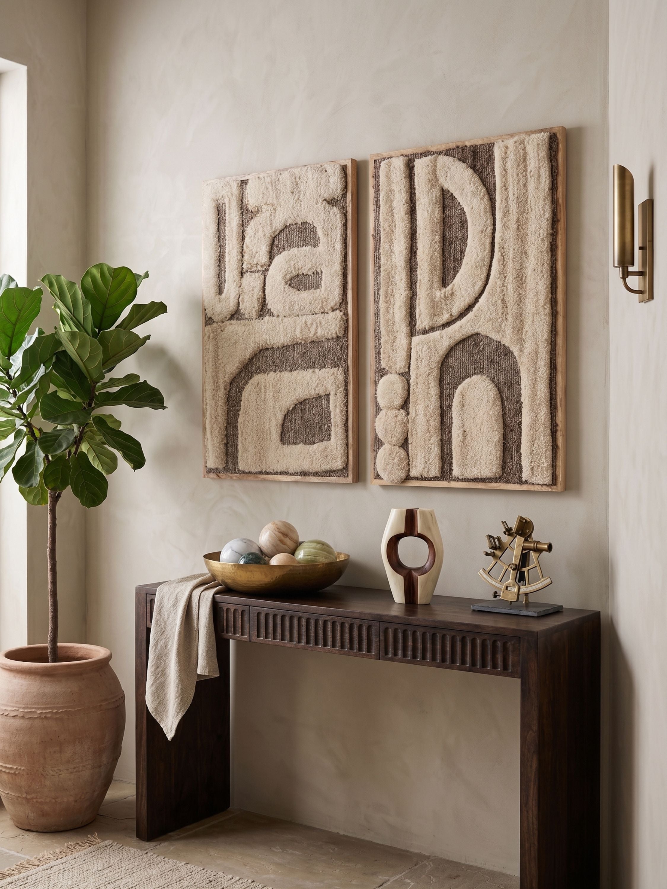 Set of two tufted wool wall art panels with abstract geometric forms in ivory and warm brown tones, displayed above a wooden console in a neutral interior
