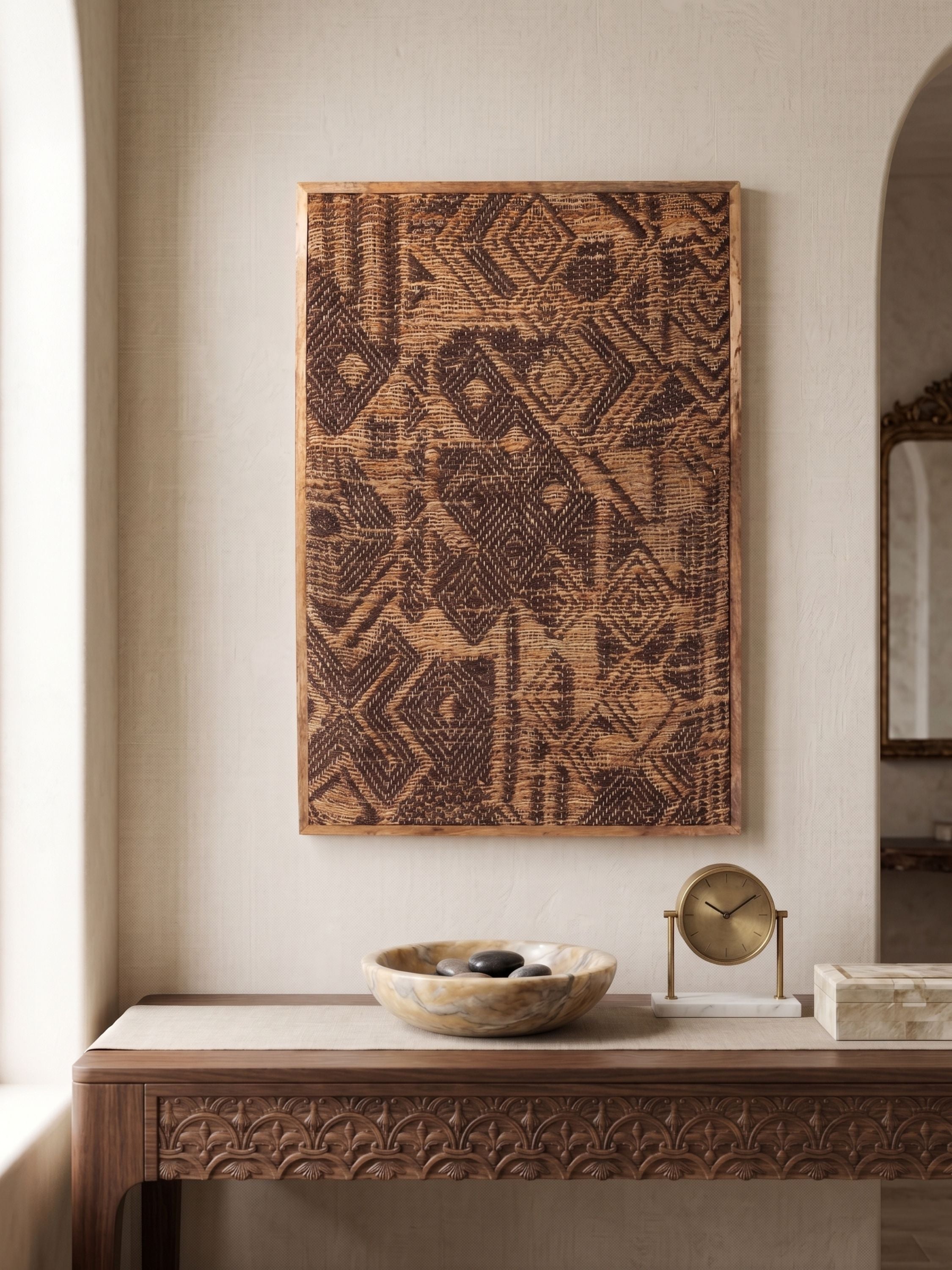 Natural jute wall art with tonal geometric pattern in brown hues, framed in wood and styled above a console with decorative objects in a neutral setting