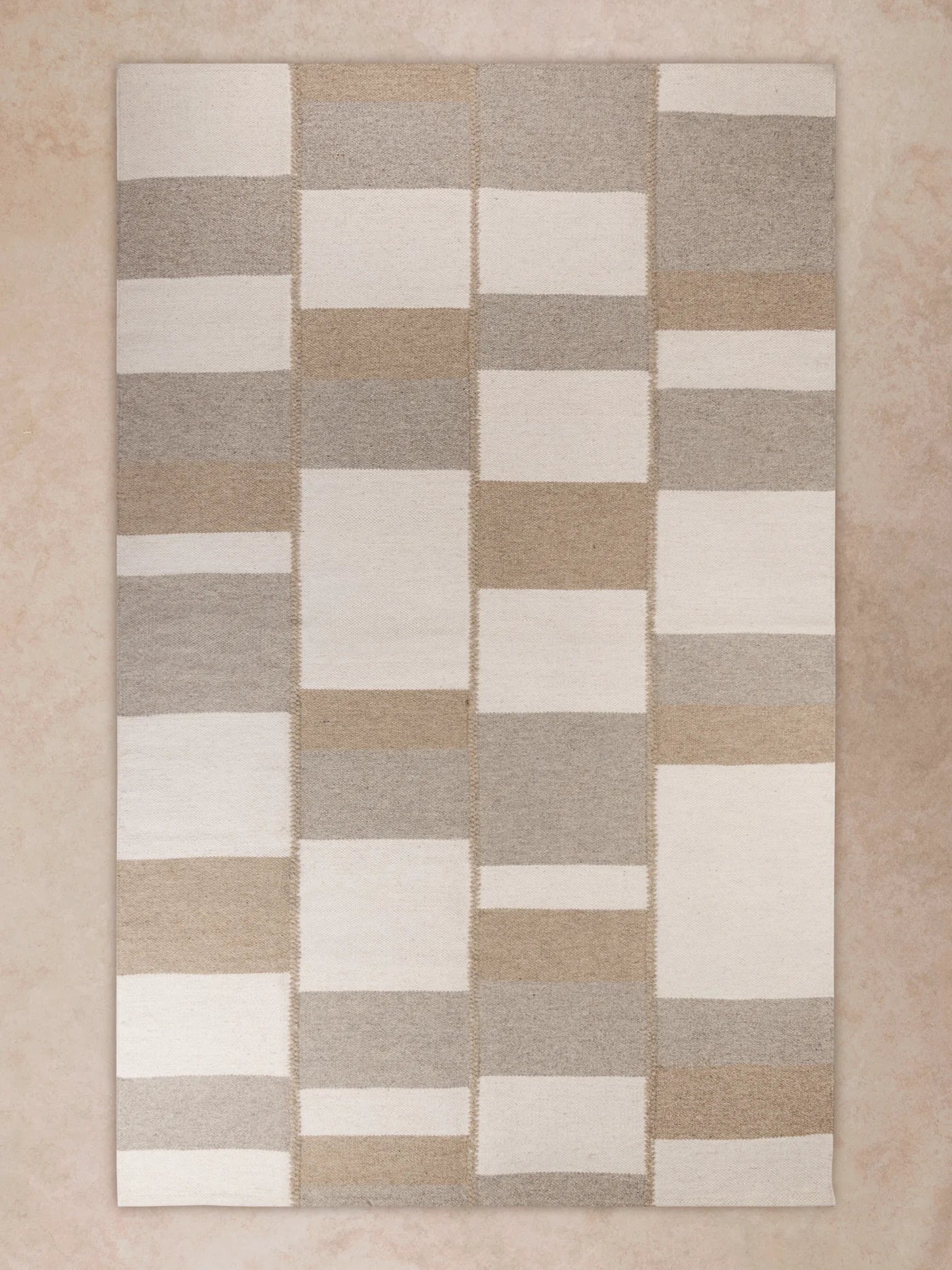 Handwoven area rug with tonal checkerboard pattern in warm beige and taupe tones shown in motion, with shifting light revealing subtle pile variation, block transitions, and surface depth