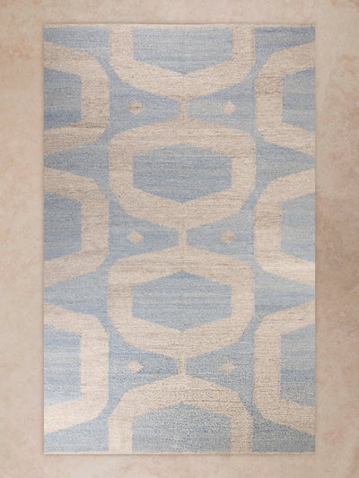 Handwoven area rug with geometric pattern in soft blue and beige tones shown in motion, with shifting light revealing woven texture, tonal variation, and surface depth