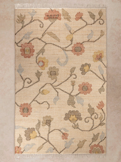 Handwoven floral area rug in beige and muted tones shown in motion, with shifting light revealing weave texture, fringe detail, and soft color variation